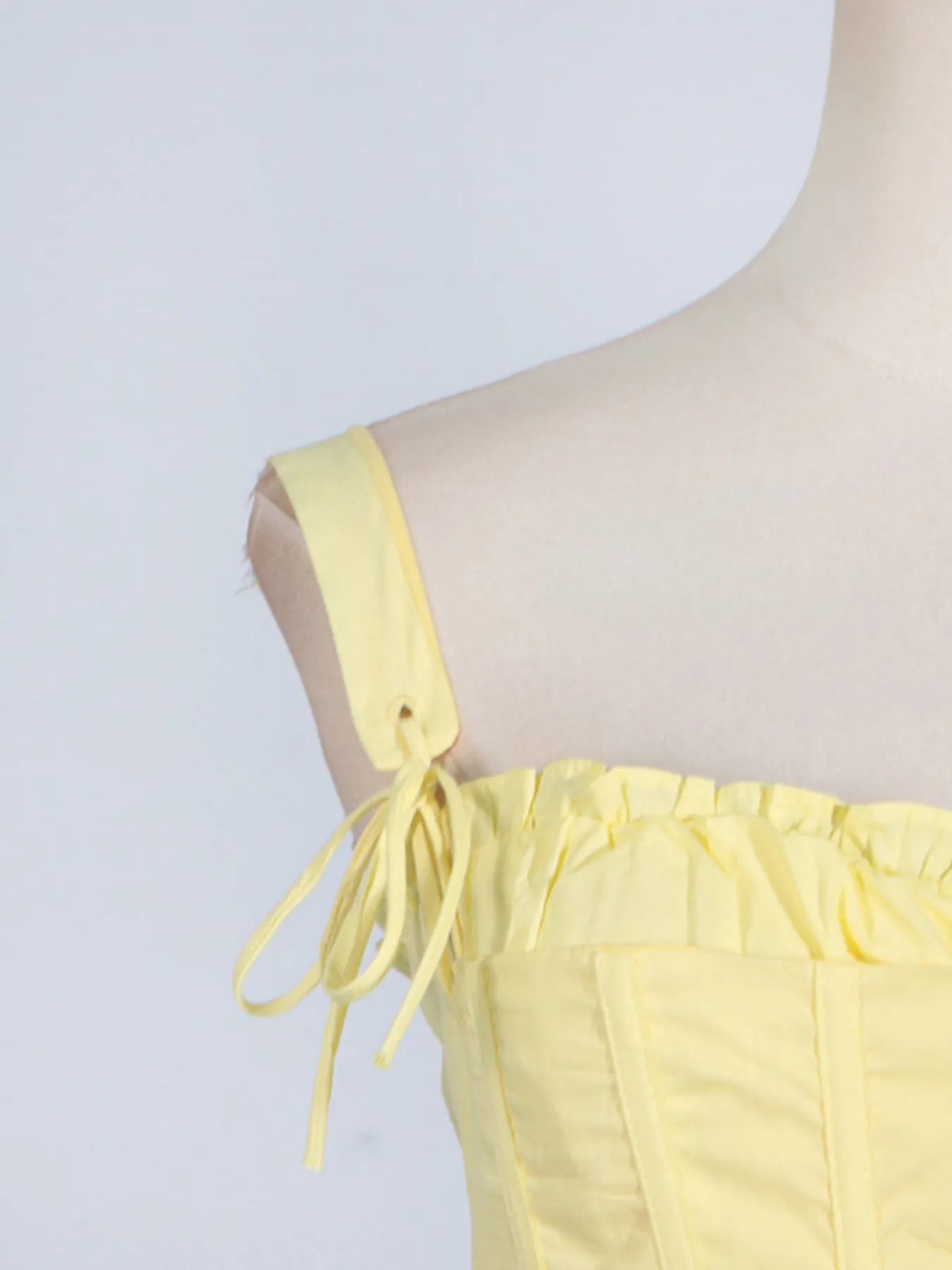 Side view of the trendy slit sleeveless midi dress with tie detail at the shoulder, perfect for adding a stylish touch to your wardrobe in striking yellow.