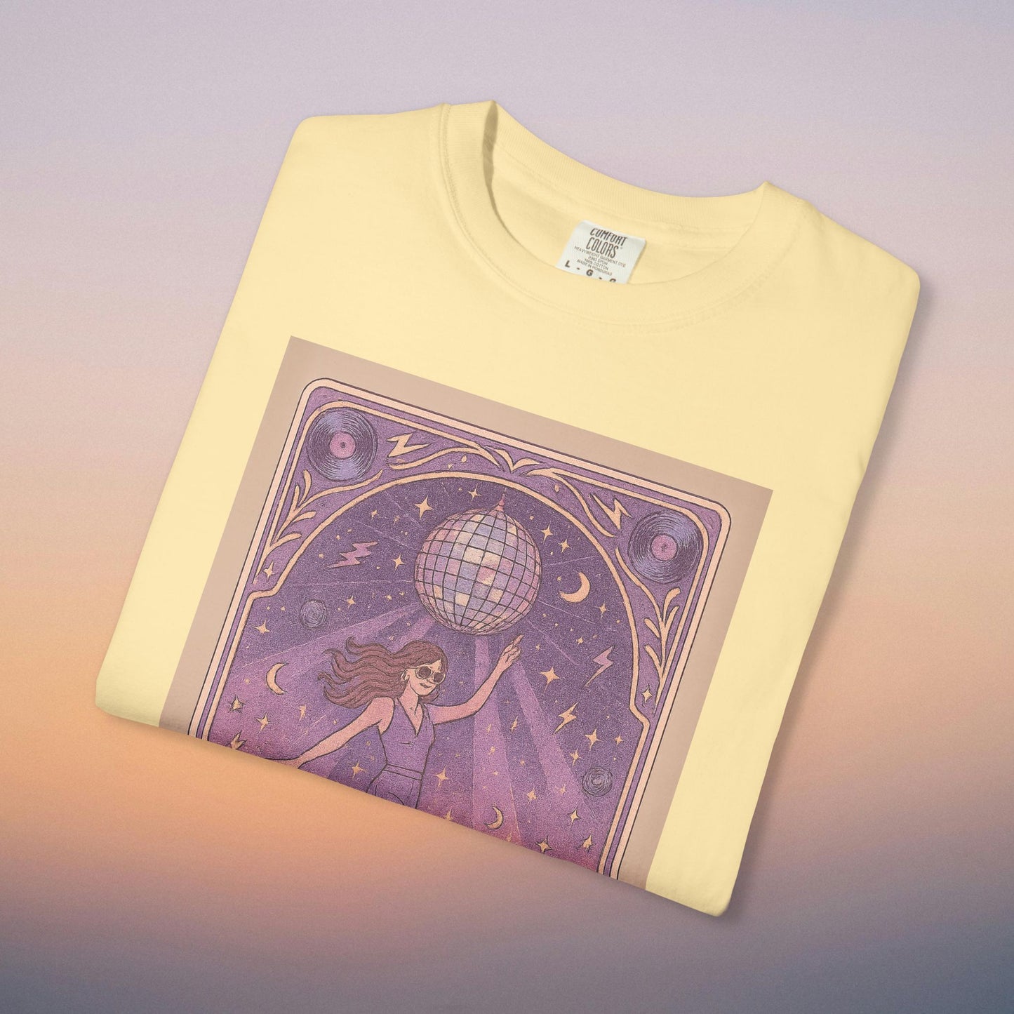 Groove Tarot Graphic Tee in soft yellow, highlighting a whimsical illustration of a woman with a disco ball, perfect for chic and playful fashion statements.