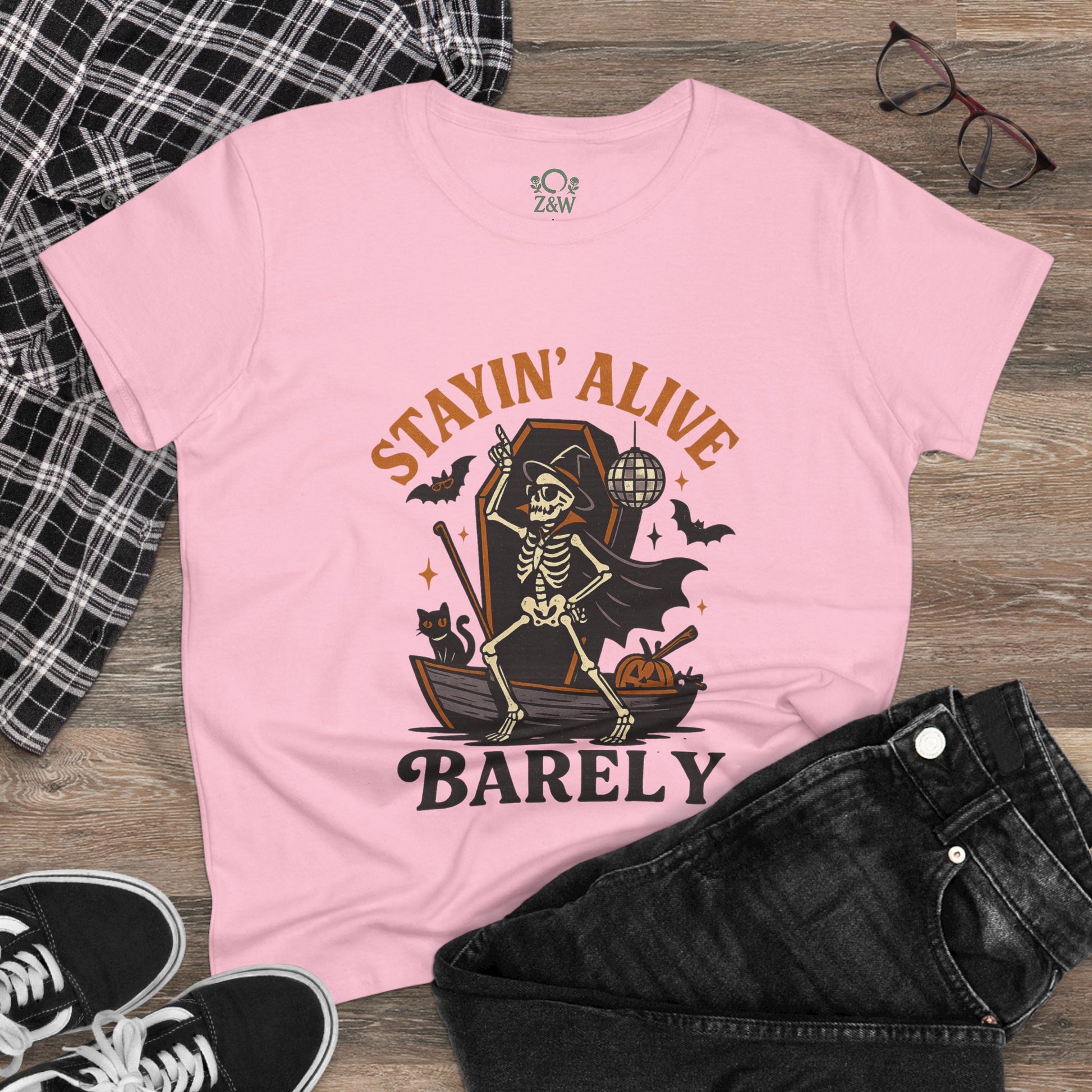 Stayin’ Alive T-Shirt featuring a whimsical skeleton design, perfect for Halloween celebrations, showcased in a playful pink color.