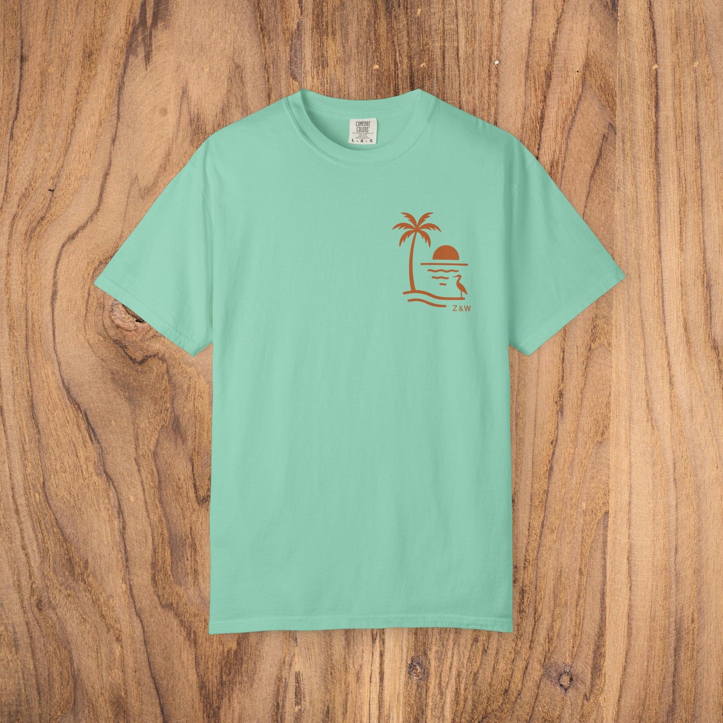 Unisex Sunset Palm Tree T-Shirt in mint green, made from vibrant garment-dyed cotton, showcasing a stylish palm tree design, available in 58 colors.