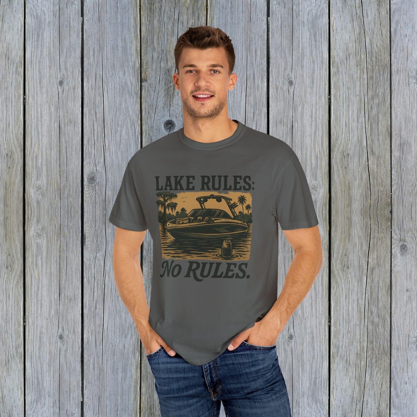 Model wearing a Unisex Garment-Dyed Lake Rules Tee in gray, showcasing a vintage boat graphic and the phrase 'LAKE RULES: No RULES.' Ideal for lake lovers and outdoor activities.