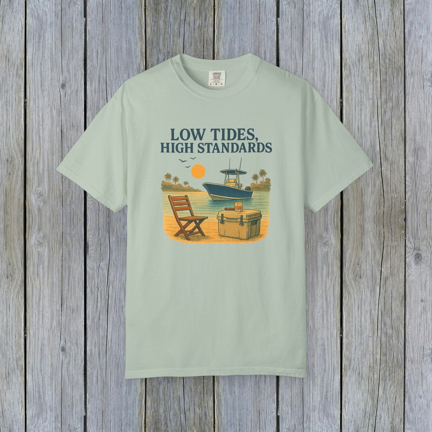 Garment-Dyed Low Tides High Standards T-Shirt in mint green, depicting a tranquil beach setting with a chair and boat. Made from soft 100% US cotton, available in sizes S-4XL.