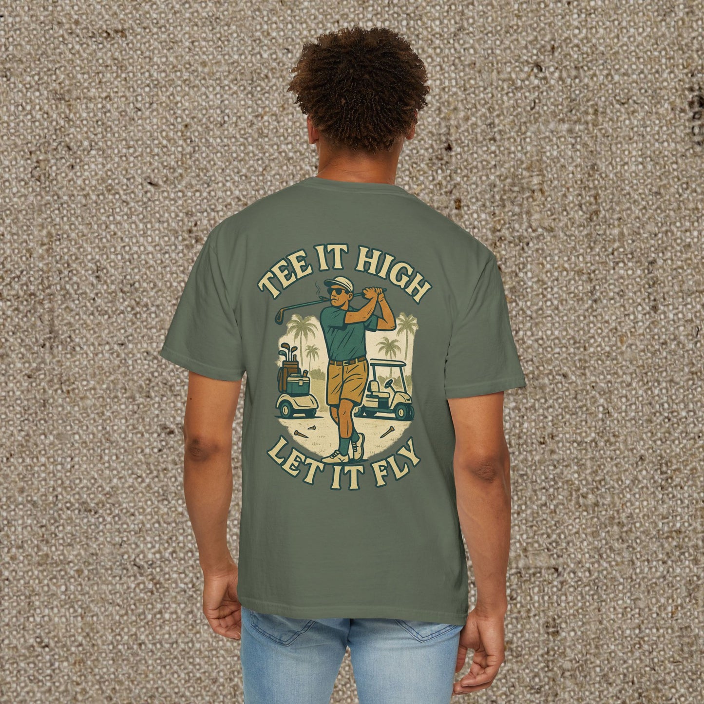 Tee It High Let It Fly Graphic Tee featuring a golfer in action, printed on a soft olive green US cotton fabric. Perfect for golf enthusiasts looking for a stylish and durable tee.