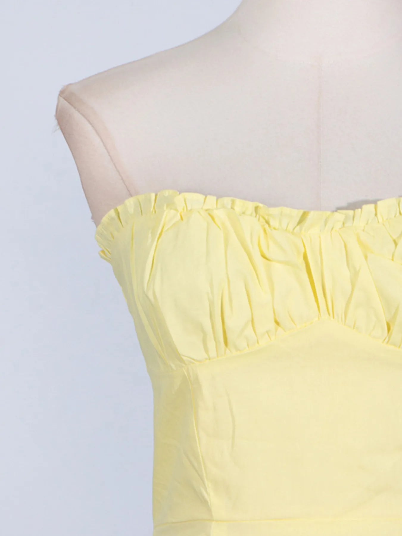 Close-up of the trendy slit sleeveless midi dress with zip back, showcasing the frill detail on the strap in a vibrant yellow color. Perfect for summer occasions.