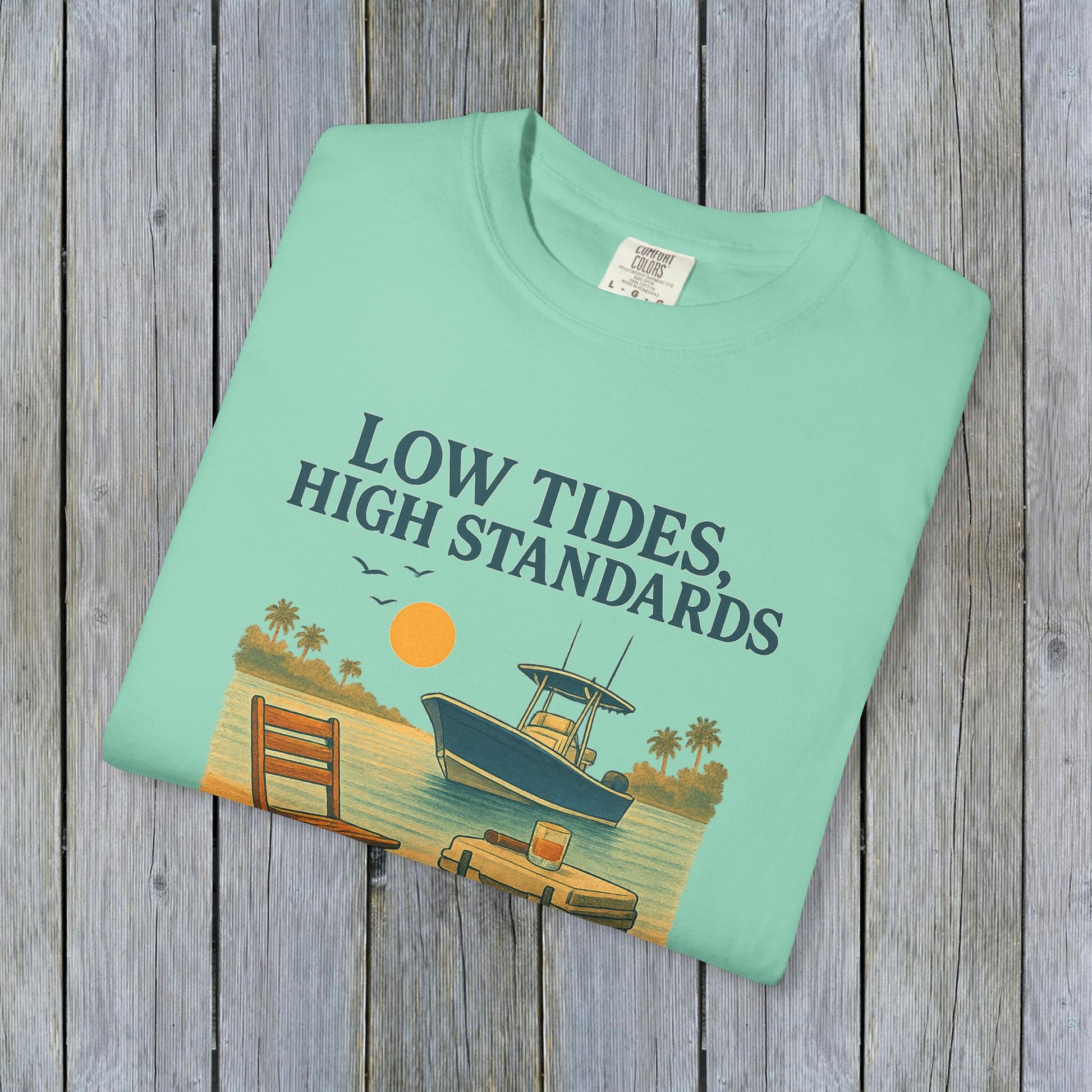 Flat lay of the Garment-Dyed Low Tides High Standards T-Shirt in mint, showcasing its soft fabric and a colorful beach design. Ideal for casual wear.