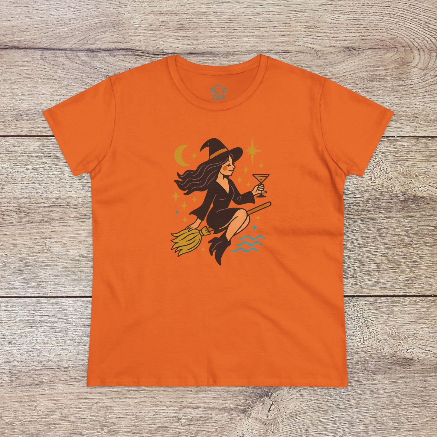 Witchy Night Out Tee in vibrant orange displaying a playful witch flying with an hourglass, surrounded by stars, made from ethically sourced 100% cotton for durability.