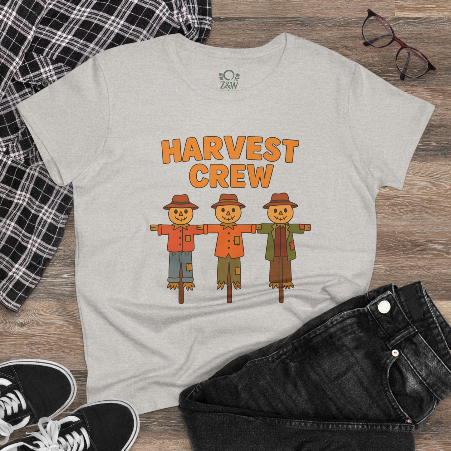 Casual setting displaying the Harvest Crew Halloween T-Shirt styled with black jeans, featuring colorful scarecrow artwork made from eco-friendly materials.
