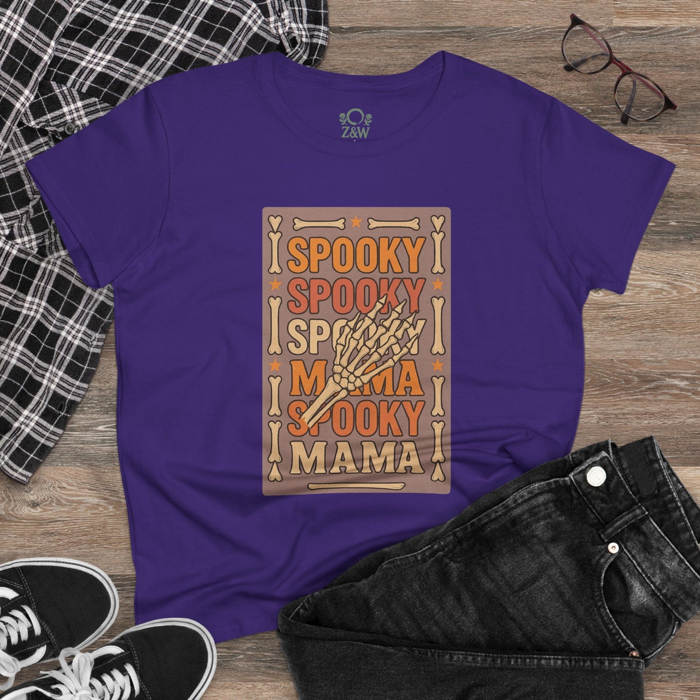 Casual styling of the Spooky Mama Tee in purple with a skeleton hand graphic, paired with black jeans and sneakers, showcasing its versatility and comfort for any occasion.