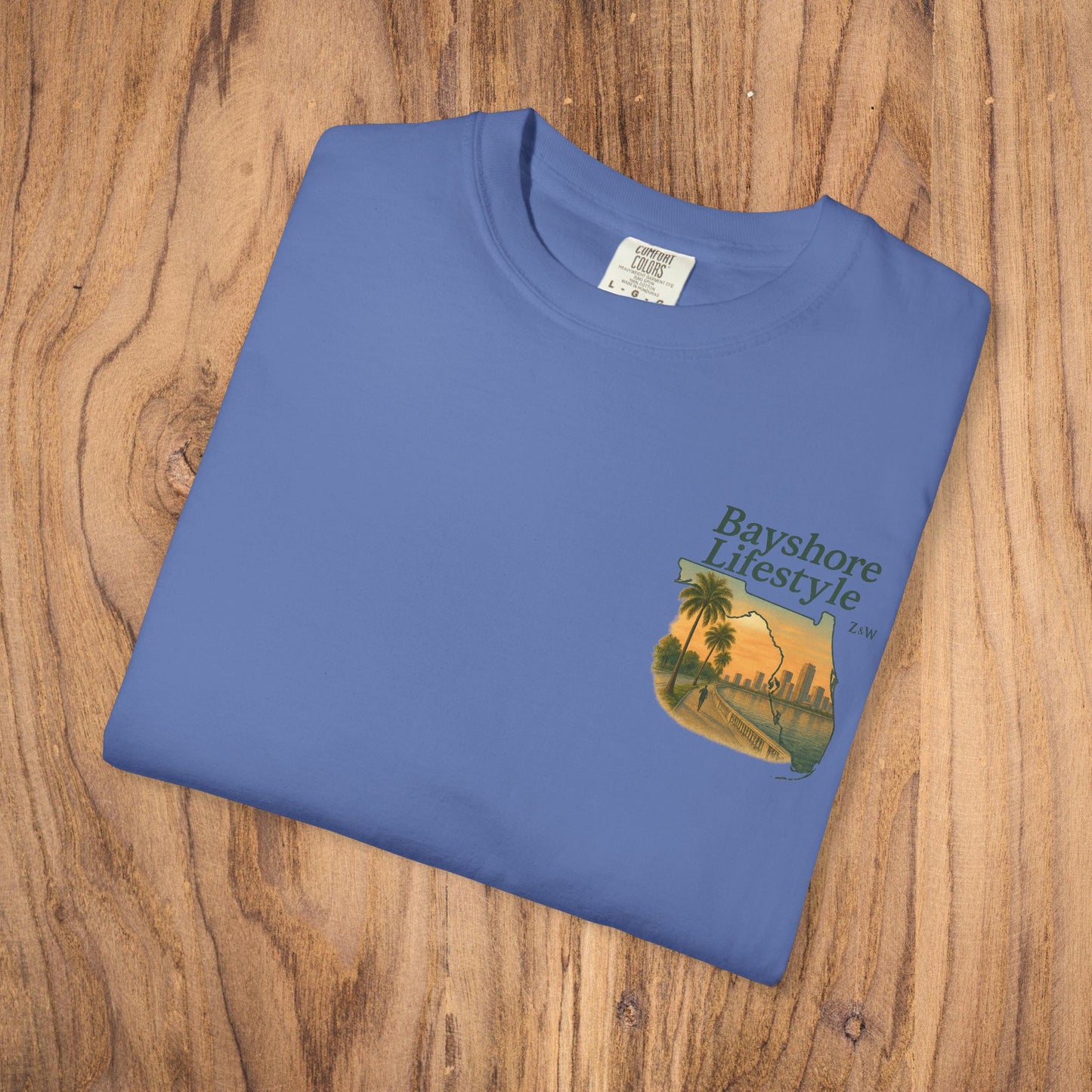 Detail shot of the Bayshore Lifestyle Tee folded neatly, showing the vibrant blue color and elegant palm tree design on the left chest.