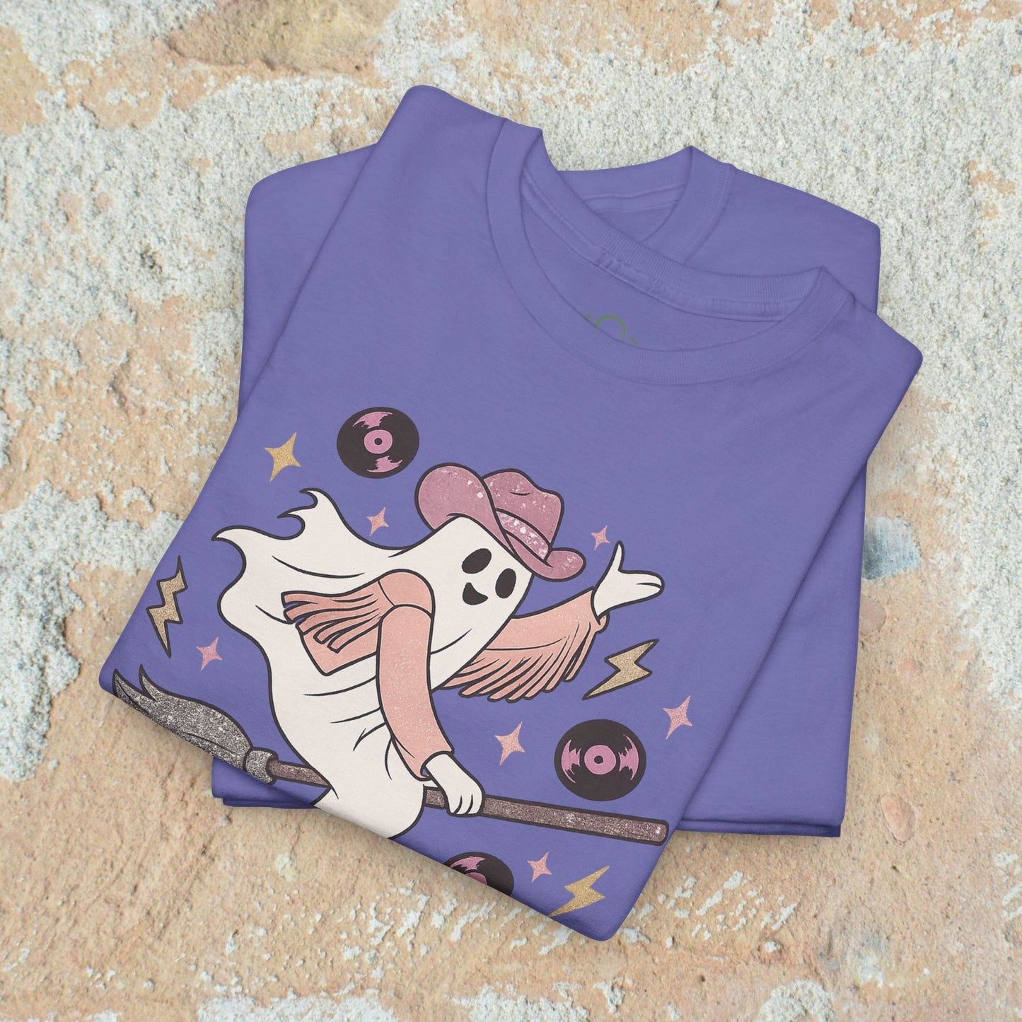 Spooky Cowgirl Graphic Tee in purple stacked view, emphasizing the playful design of a ghost cowgirl on a broom with vinyl records. Eco-friendly and soft fabric, available in sizes S-5XL.