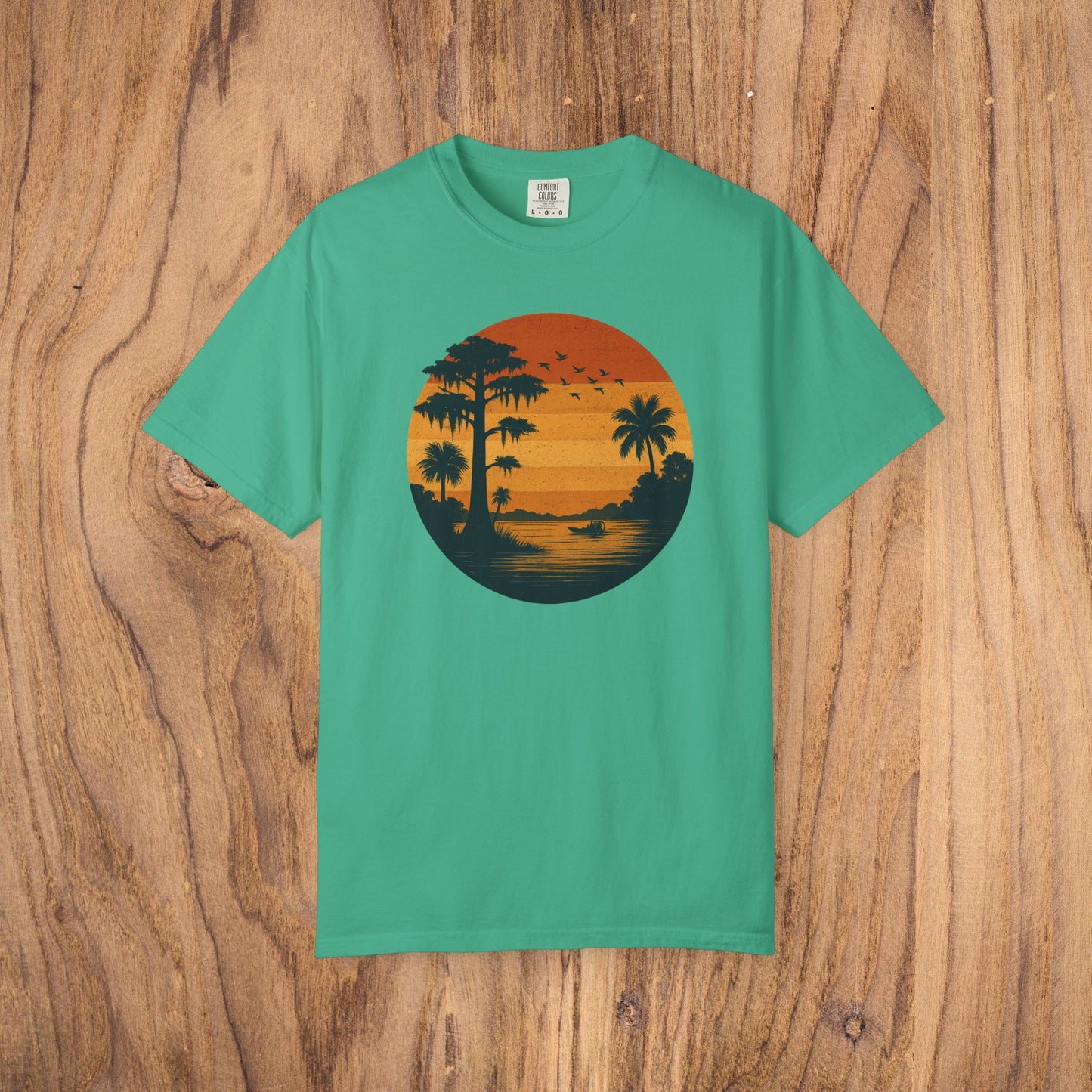 Unisex Garment-Dyed Sunset Tee in bright teal displaying a sunset scene with palm trees, a stylish choice for casual gatherings.