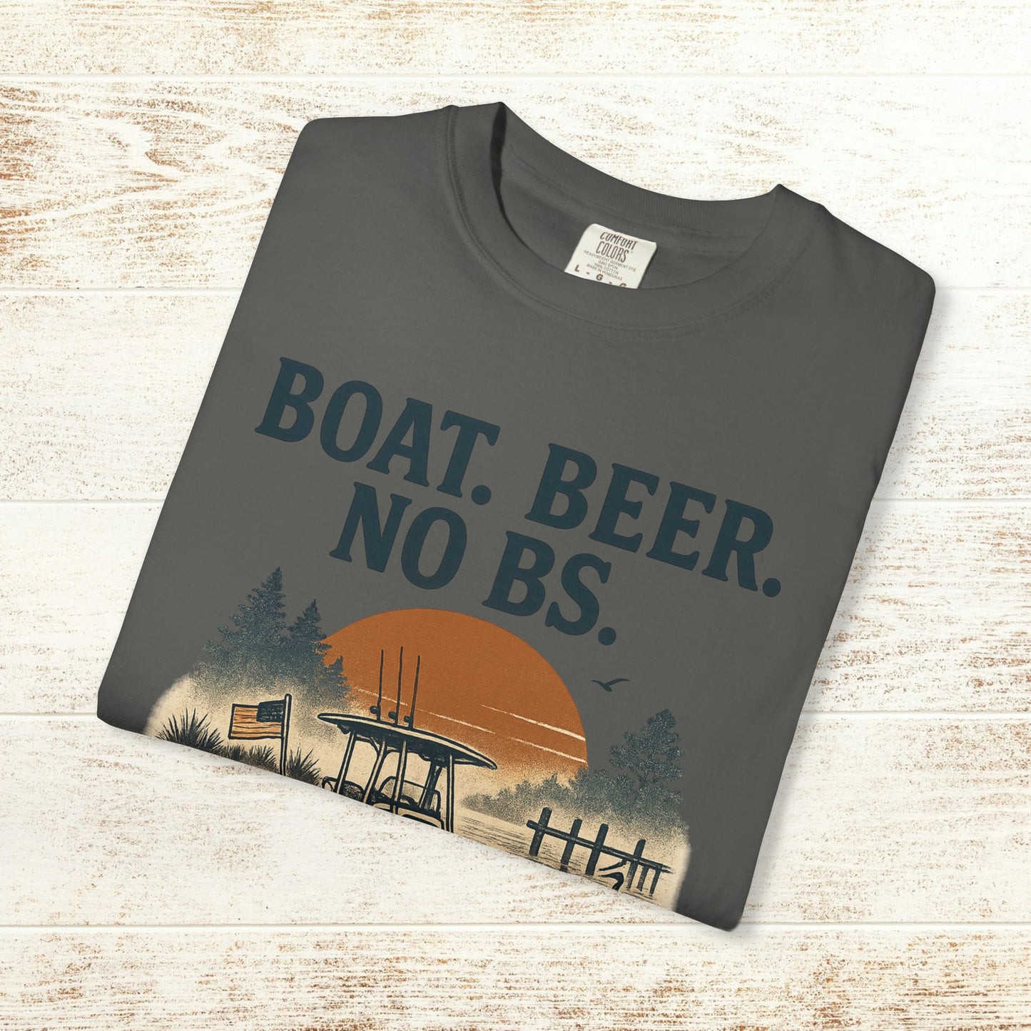 Boat Beer No BS Tee displayed on a wooden table in charcoal color, featuring a scenic sunset and boat graphic.
