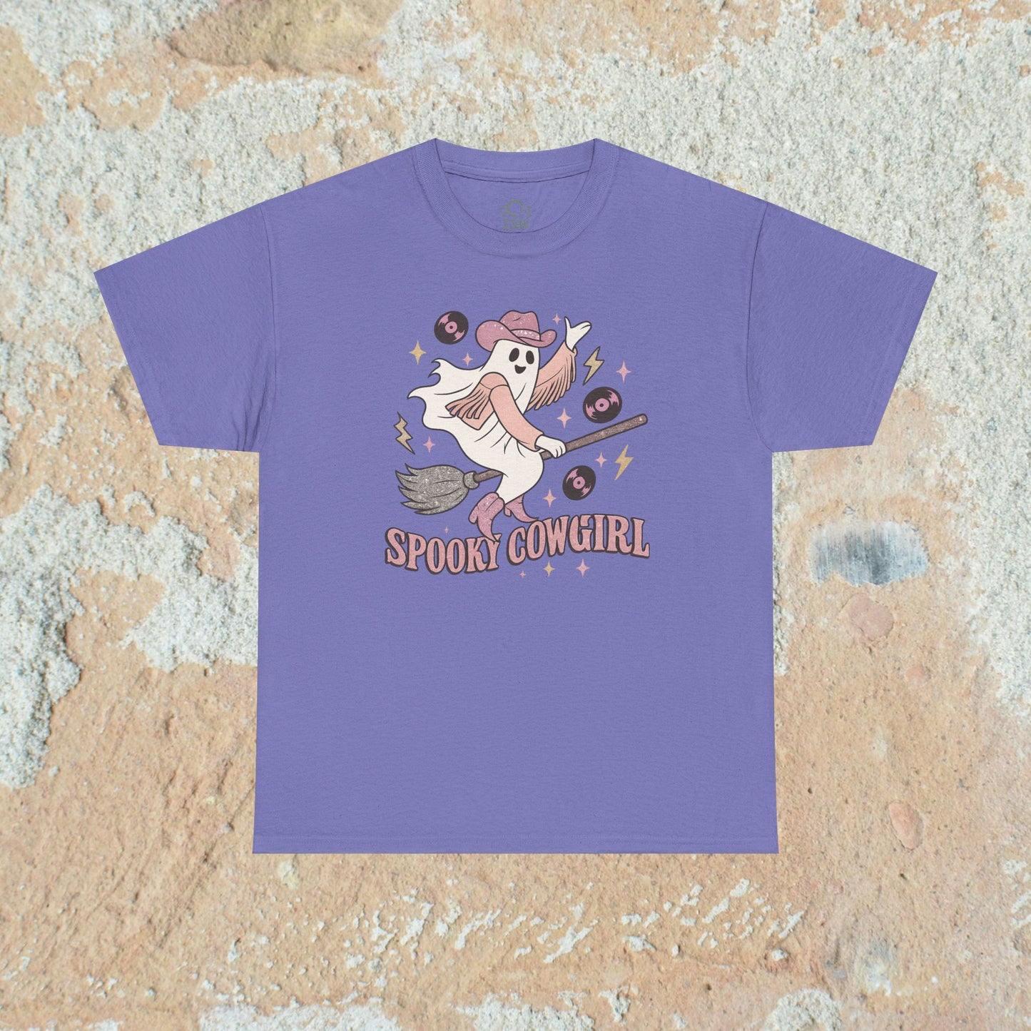 Charming purple Spooky Cowgirl graphic tee depicting a spirited ghost on a broomstick with music records, a fun choice for Halloween celebrations. Available in sizes S to 5XL.