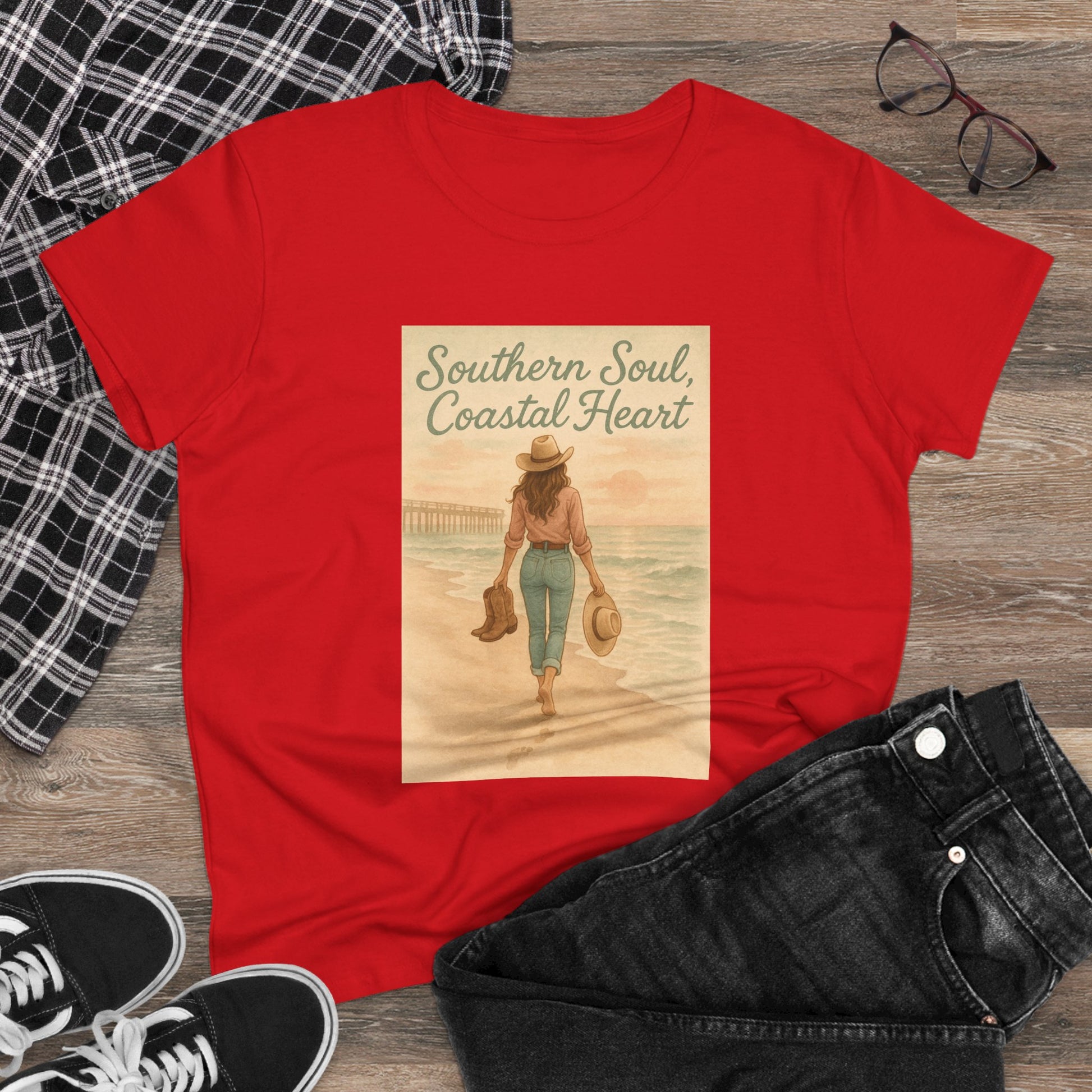 Southern Soul Coated Heart Tee in red on a wooden surface, featuring a charming illustration of a woman by the waterfront. A great addition to any casual wardrobe, perfect for expressing your coastal soul.