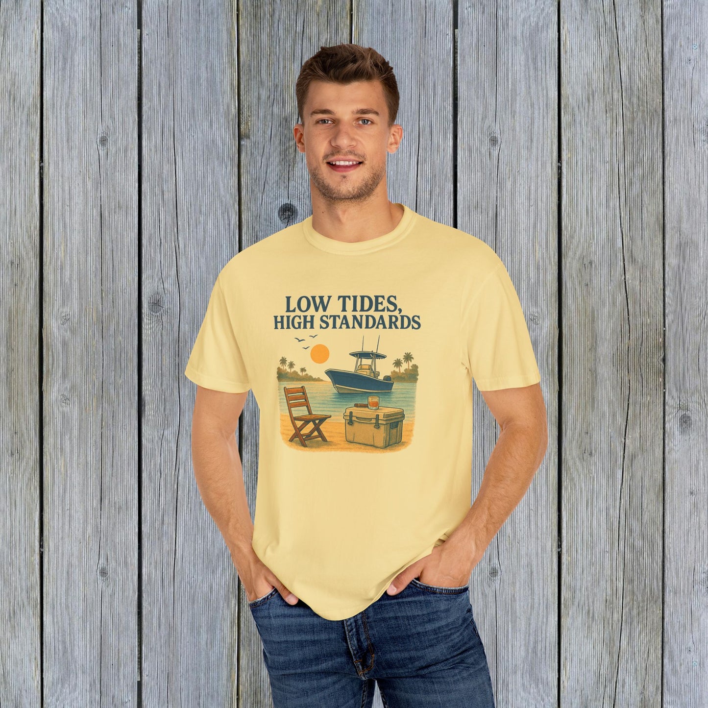 Man wearing the Garment-Dyed Low Tides High Standards T-Shirt in yellow, featuring a vibrant beach graphic with a boat and chair. A perfect blend of comfort and style.