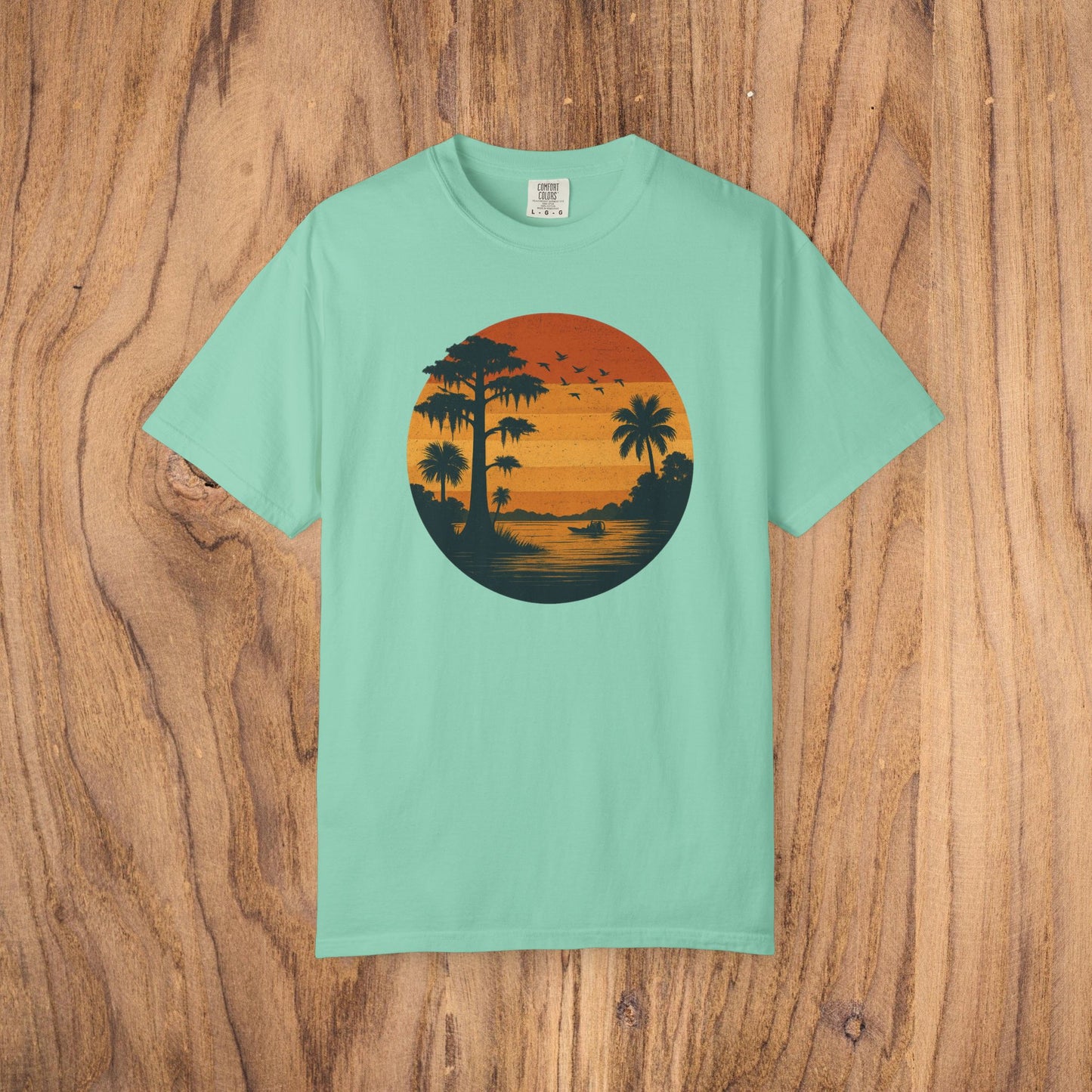 Unisex Garment-Dyed Sunset Tee in mint green showcasing a vibrant sunset graphic with palm trees, ideal for laid-back occasions, available from S to 4XL.