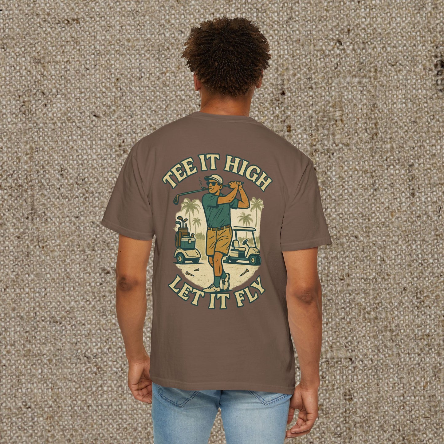Tee It High Let It Fly Graphic Tee in brown, displaying a golfer's back swing with palm trees and golf carts. A must-have for avid golfers.