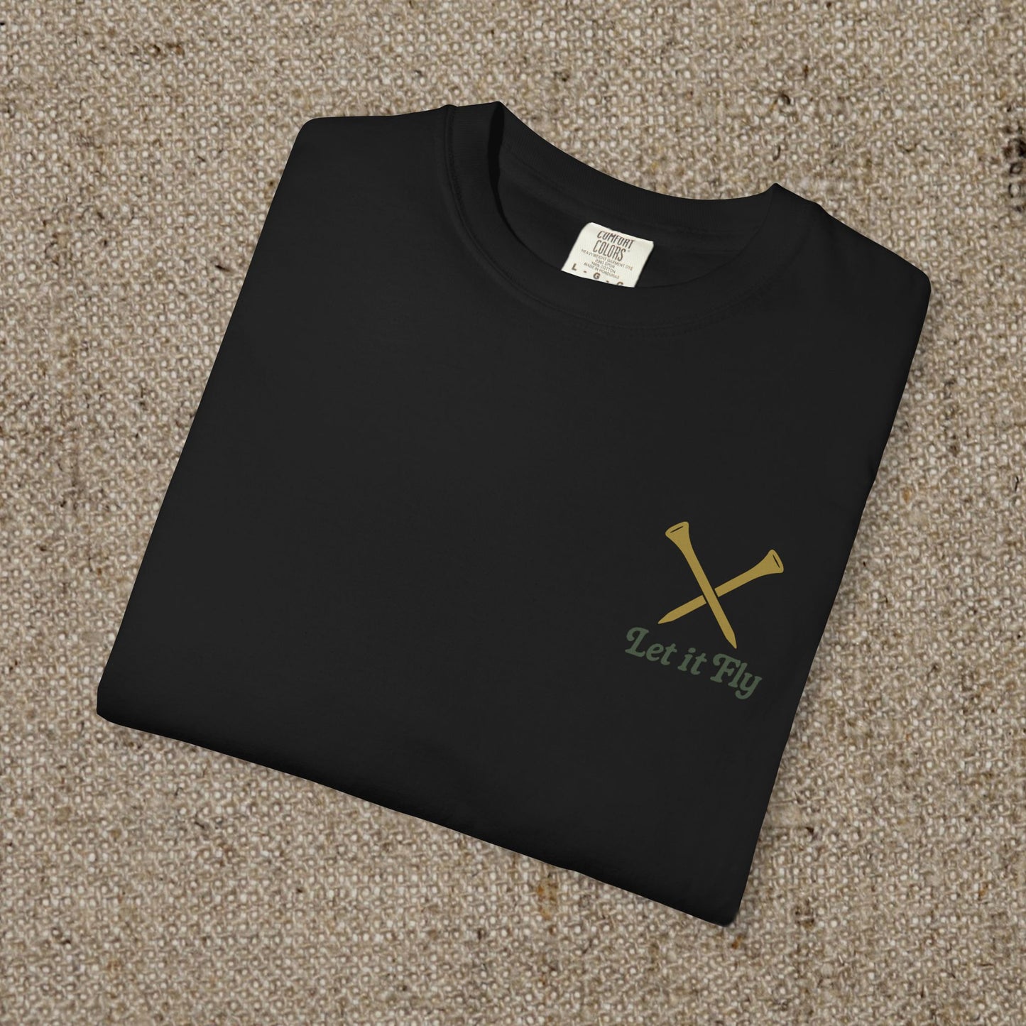 Folded Tee It High Let It Fly Graphic Tee showcasing a minimalist design with crossed golf clubs and the phrase 'Let it Fly', ideal for casual wear.