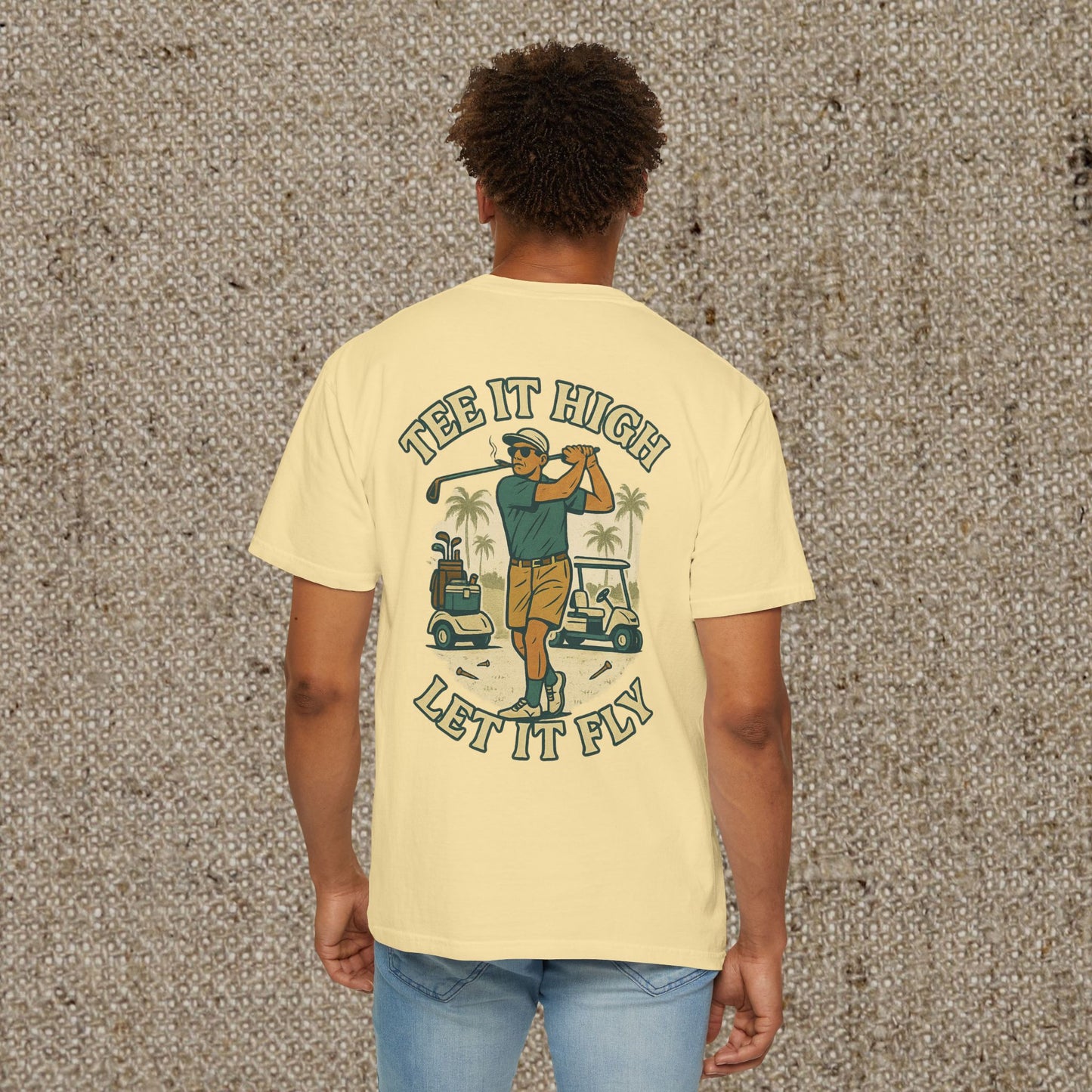 Tee It High Let It Fly Graphic Tee in yellow, featuring a golfer swinging with palm trees and golf carts in the background. Ideal for golf enthusiasts.