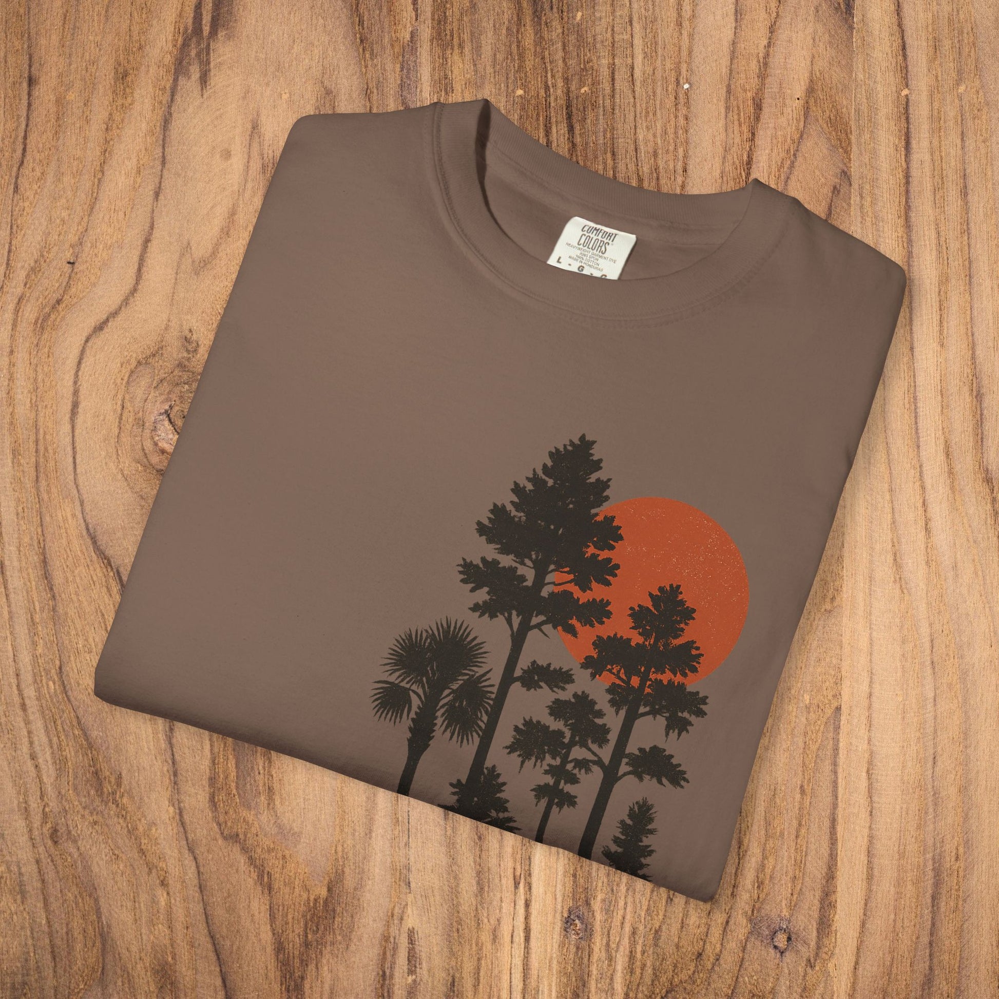 Folded Sunset Trees Unisex T-Shirt in brown, emphasizing the intricate sunset and tree design on soft 100% cotton material.