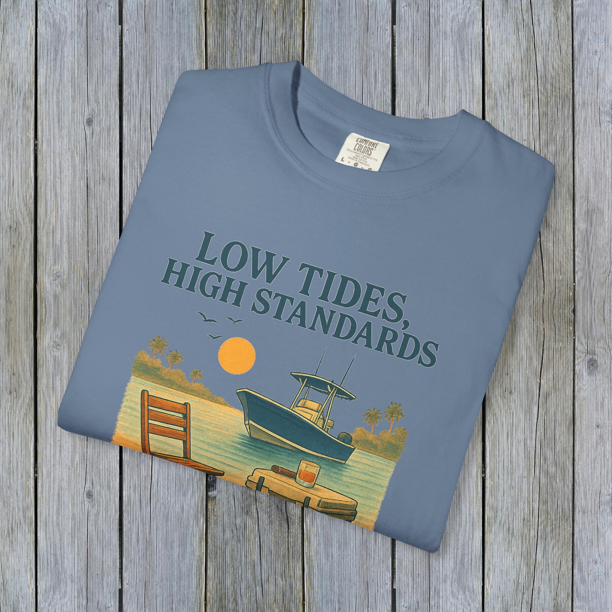 Folded Garment-Dyed Low Tides High Standards T-Shirt in soft blue, featuring a vibrant beach scene with a boat, suitable for everyday wear.