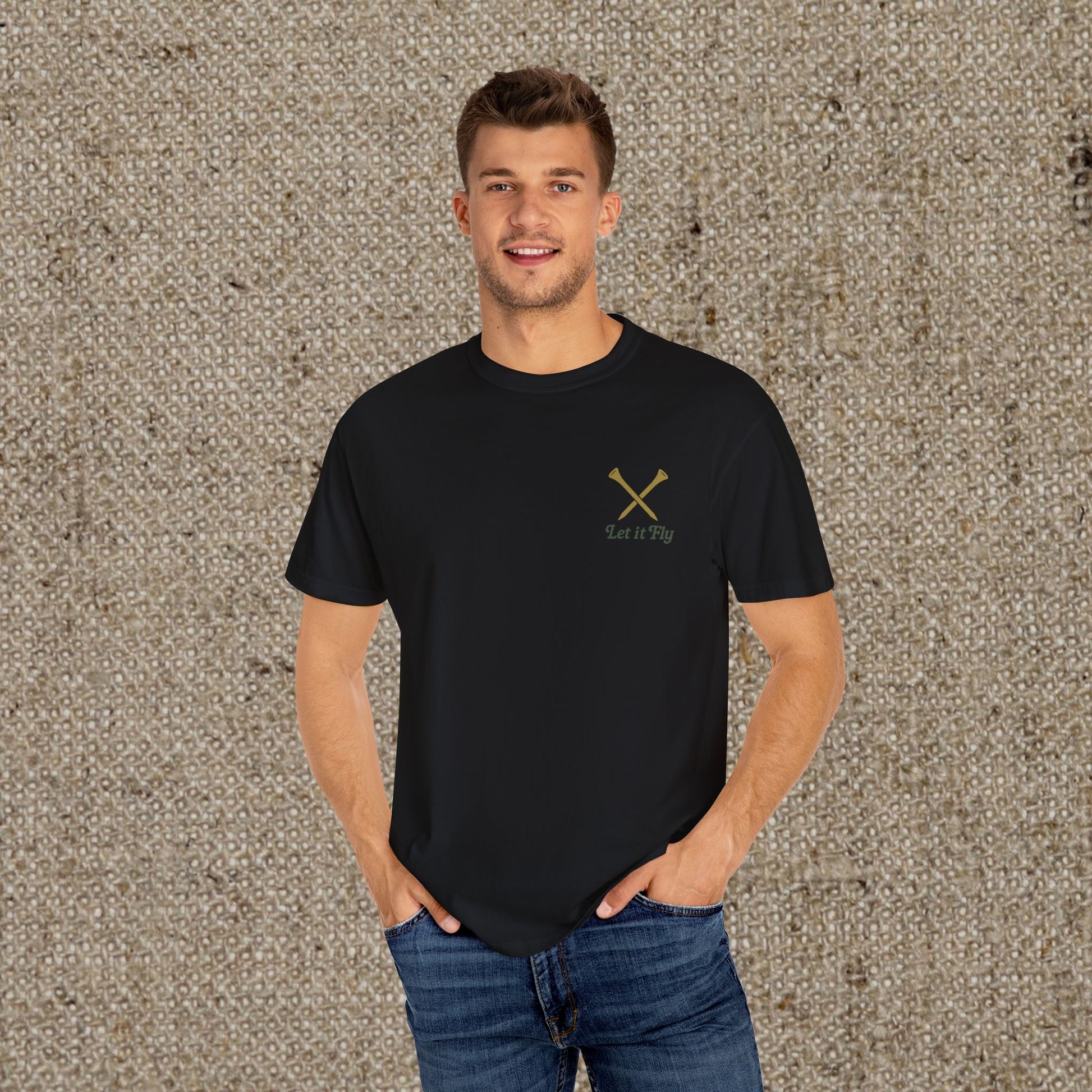 Man wearing the Tee It High Let It Fly Graphic Tee with a stylish fit, featuring crossed golf clubs and the phrase 'Let it Fly', suitable for any occasion.