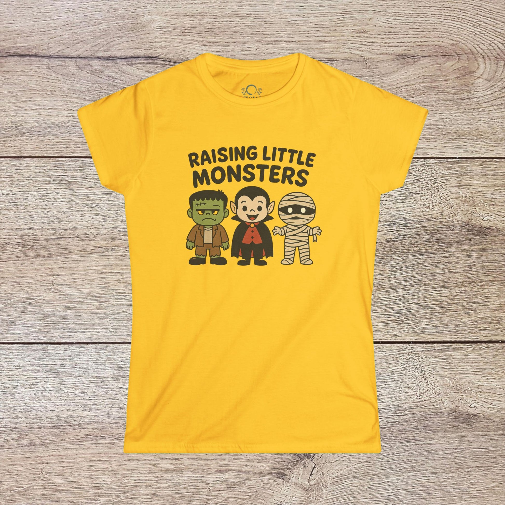 Bright yellow Halloween Family T-Shirt with playful illustrations of a Frankenstein monster, Dracula, and a mummy, along with 'Raising Little Monsters' text. Great kids tee for Halloween festivities.
