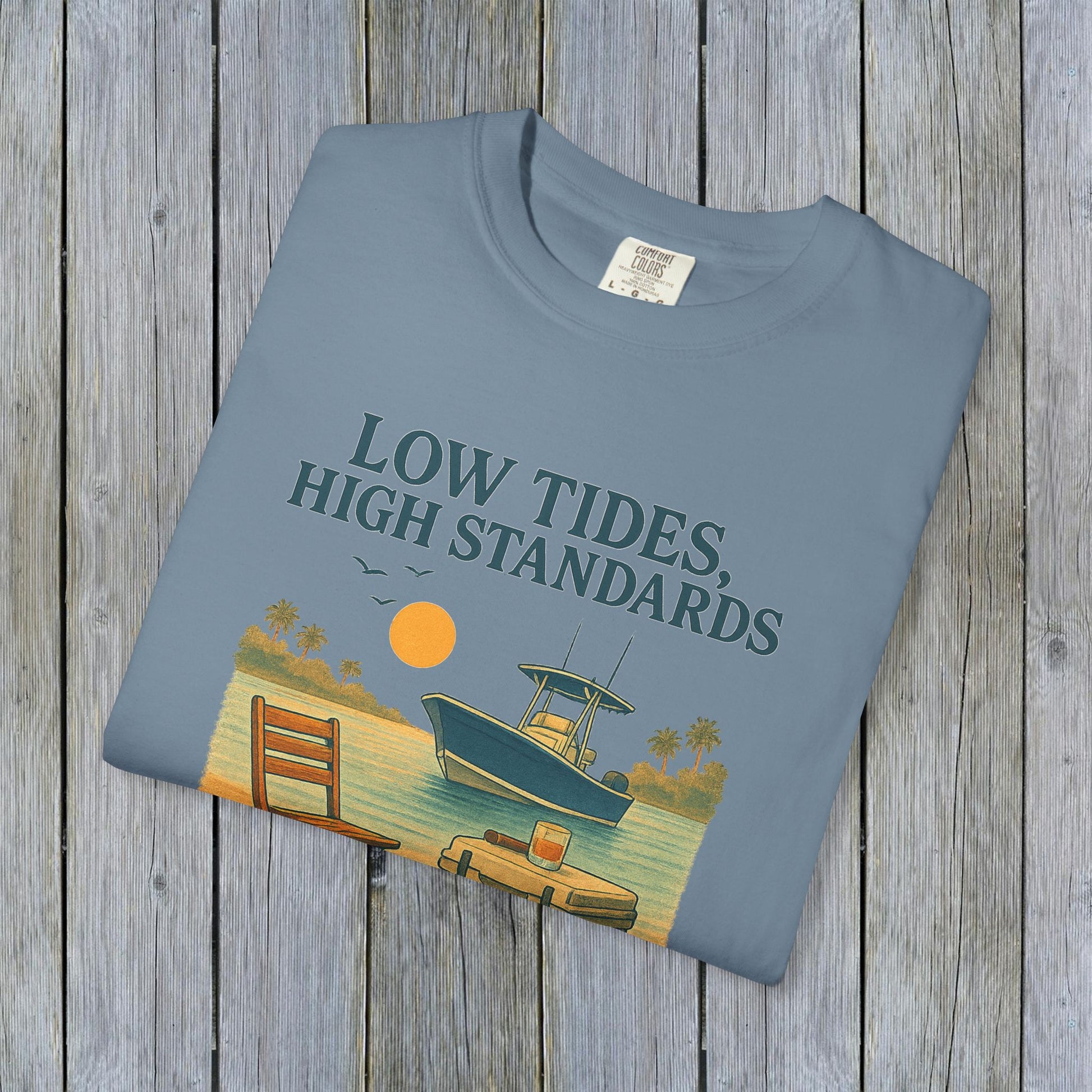 Garment-Dyed Low Tides High Standards T-Shirt in light blue, displaying a serene beach scene with a boat and sunset, offering comfort and style.
