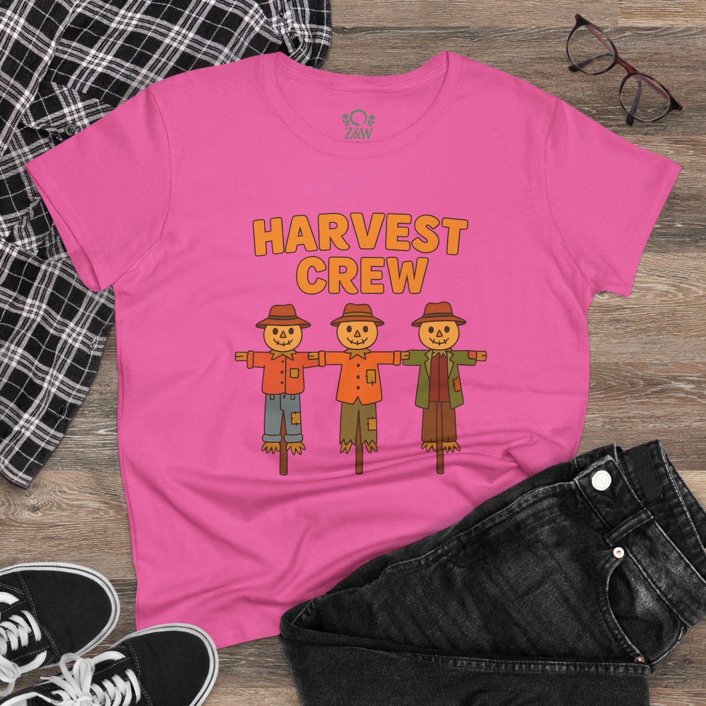 Harvest Crew Halloween T-Shirt in pink laid flat with stylish accessories, featuring a fun scarecrow print, ideal for Halloween festivities.