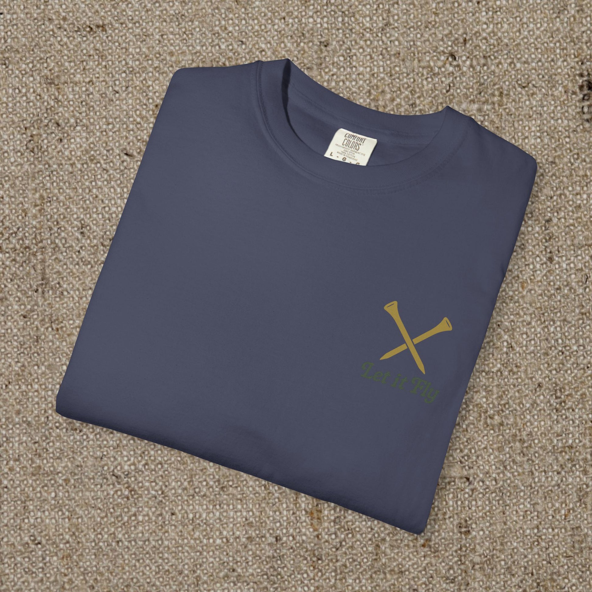 Tee It High Let It Fly Graphic Tee displayed flat, featuring a stylish design with crossed golf clubs on a navy background, made from soft US cotton for durability.