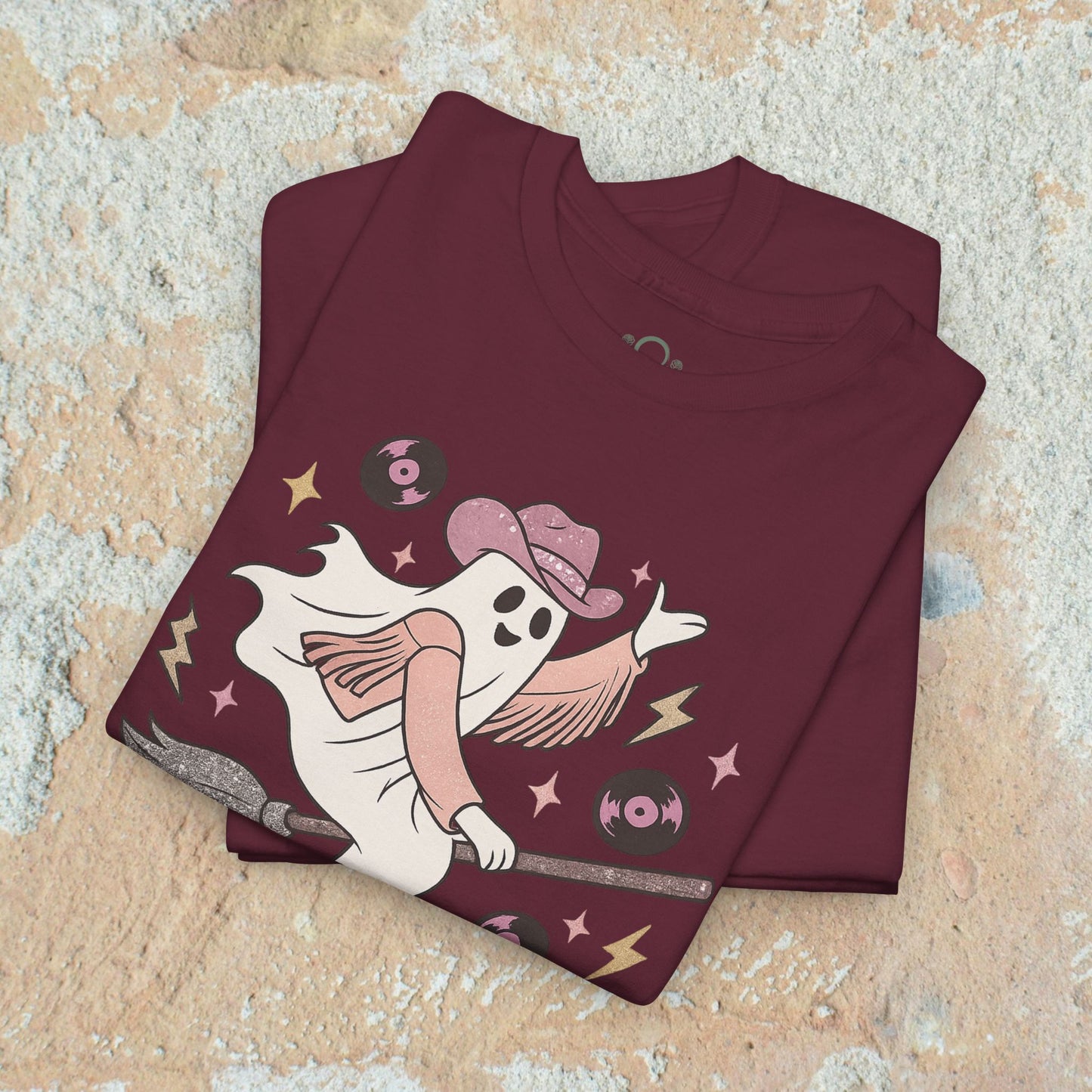 Spooky Cowgirl Graphic Tee featuring a stylish ghost character in a maroon shirt, holding a broom and wearing a cowboy hat, ideal for casual wear and available in sizes S to 5XL.