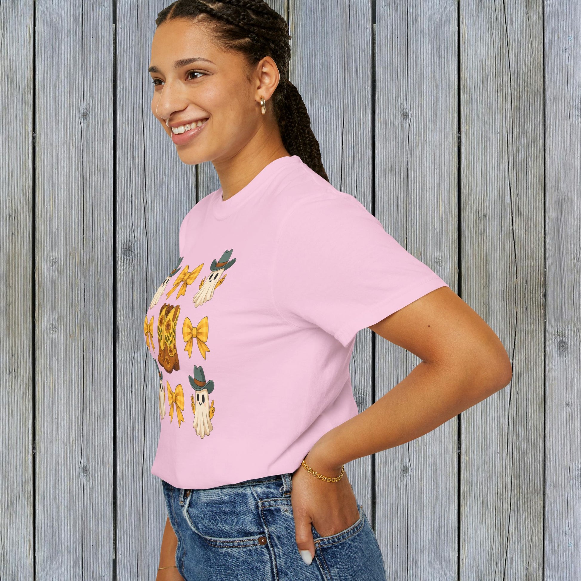 Model wearing a Cute Halloween T-Shirt with playful ghosts and cowboy boots, showcasing unisex fall fashion in eco-friendly fabric.