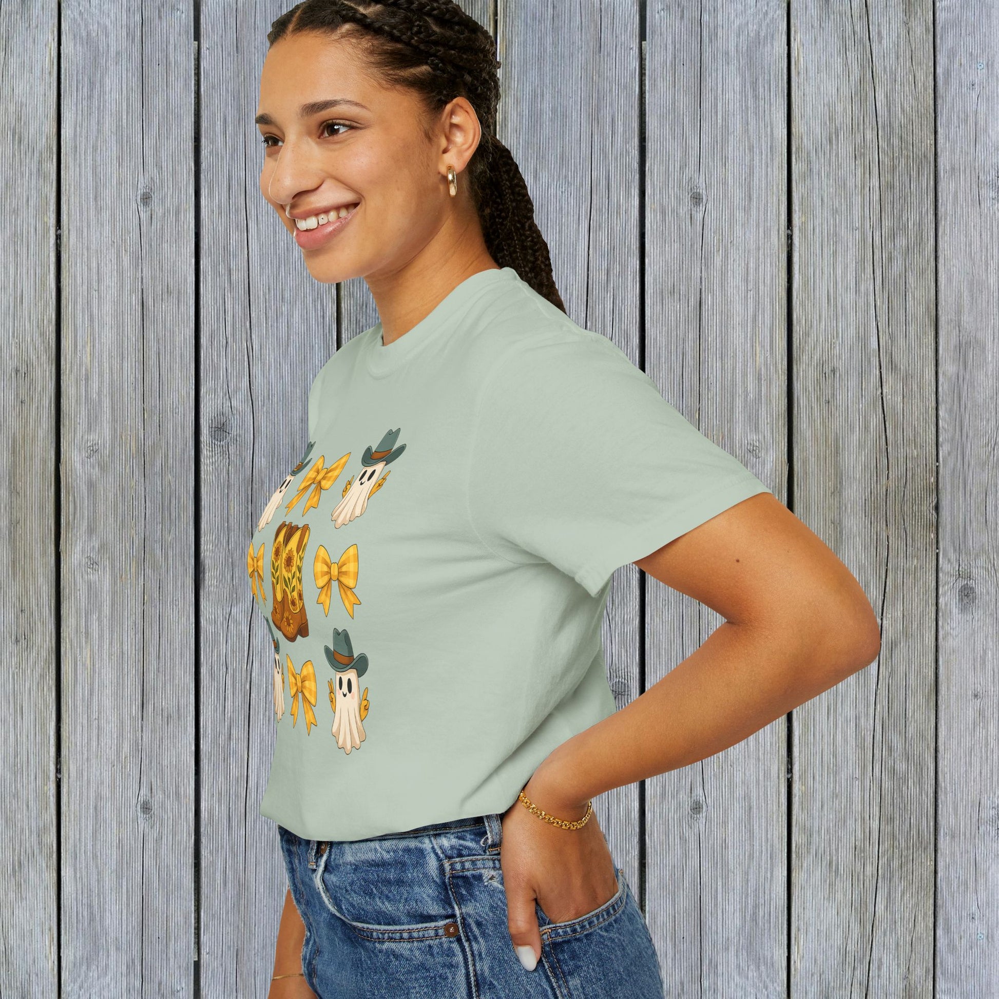 Model posing in a soft green Cute Halloween T-Shirt featuring adorable ghosts and cowboy boots, great for unisex fall fashion, utilizing eco-friendly materials.