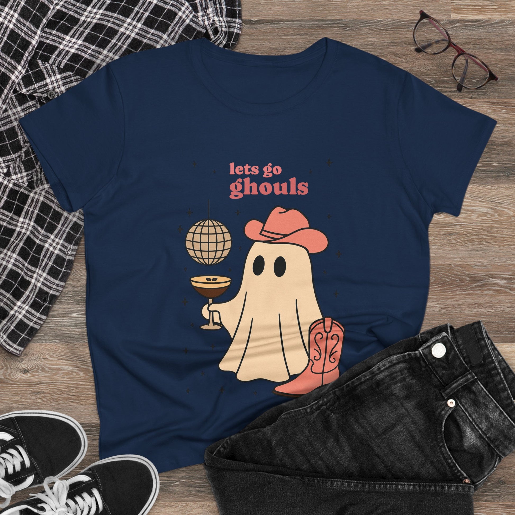 Let's Go Ghouls Tee featuring a playful ghost graphic holding a cocktail and disco ball, perfect for Halloween. Made from 100% cotton with a soft fit, available in sizes S-3XL.