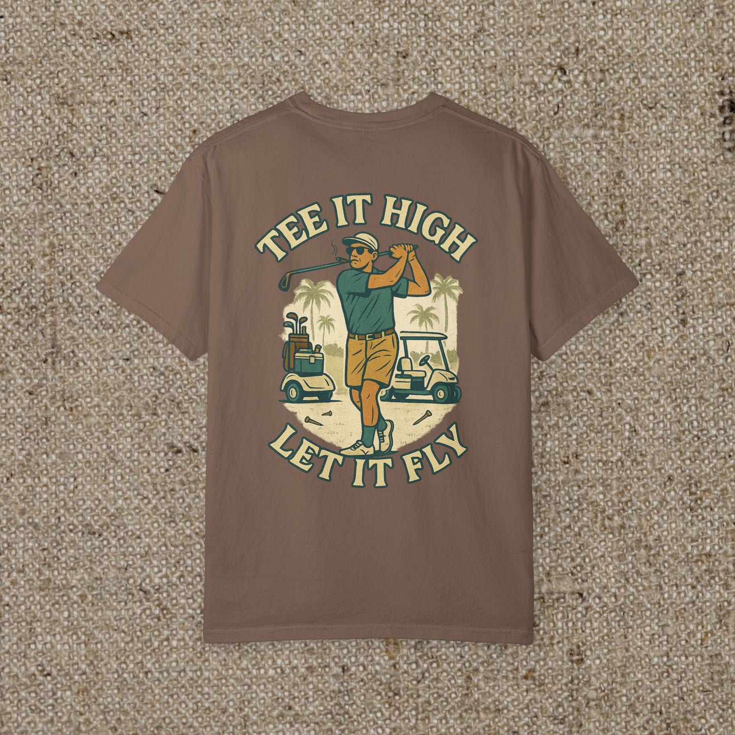 Tee It High Let It Fly Graphic Tee in brown, showcasing a golfer in action with golf carts and palm trees behind. Perfect for stylish golf lovers.