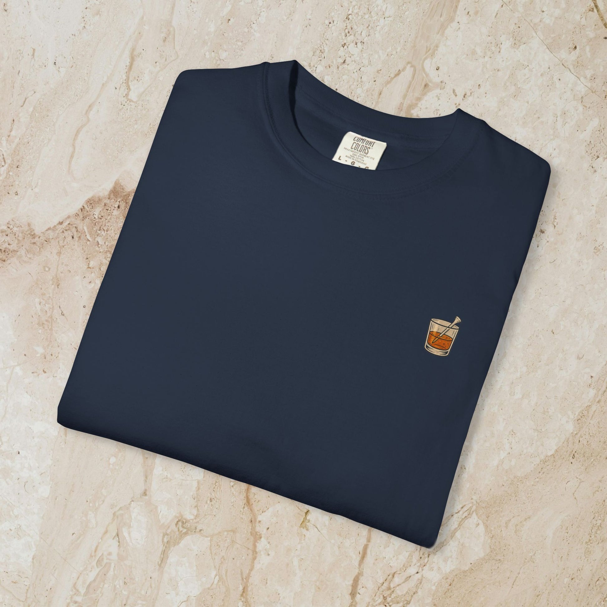 Folded Golden Whiskey Dog Tee in navy color with a small pocket graphic featuring a drink, made of 100% cotton for a relaxed fit and comfort.