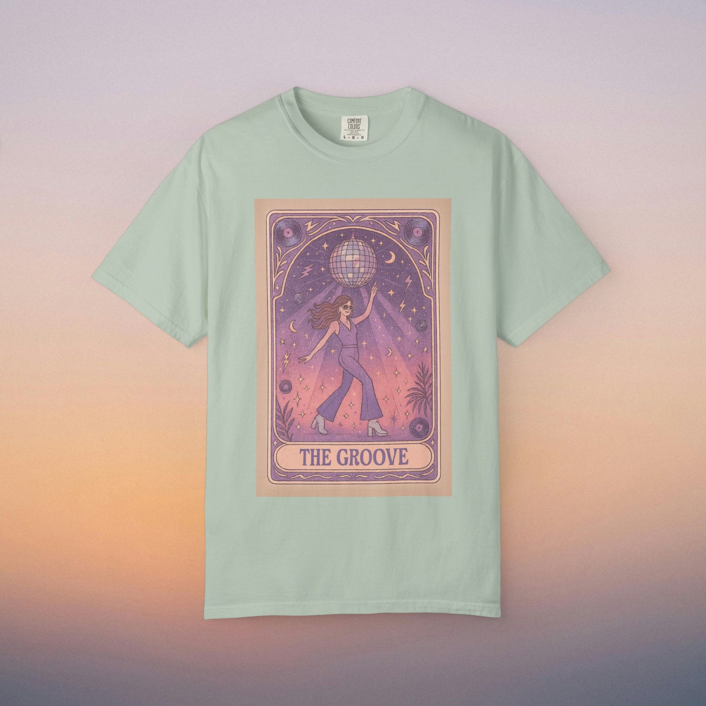 Groove Tarot Graphic Tee in mint green, featuring an enchanting illustration of a figure with a globe set in a dreamy starry scene. This 100% ring-spun cotton unisex tee is available in sizes S-4XL for a perfect fit.