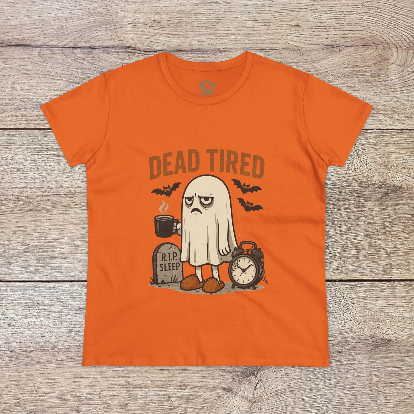 Cute Whimsical Ghost T-Shirt for Halloween in lively orange, displaying a ghost character with 'DEAD TIRED' text alongside a clock and grave, perfect for spooky fun.