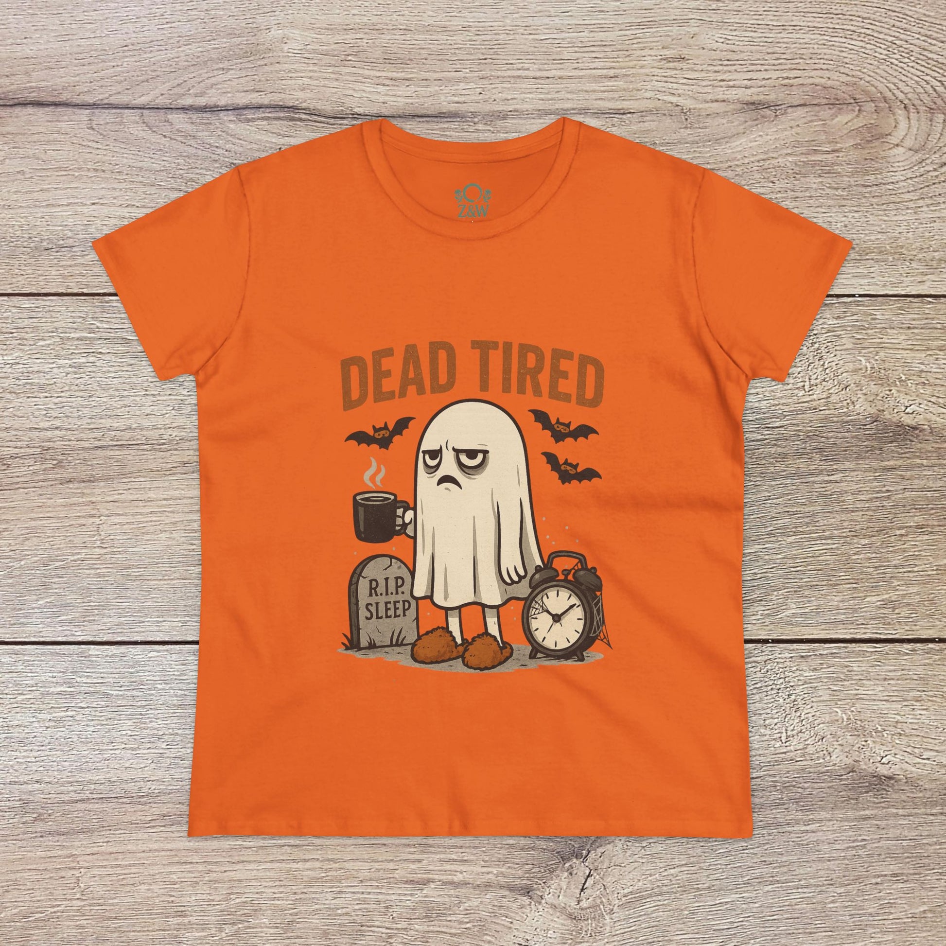 Cute Whimsical Ghost T-Shirt for Halloween in lively orange, displaying a ghost character with 'DEAD TIRED' text alongside a clock and grave, perfect for spooky fun.