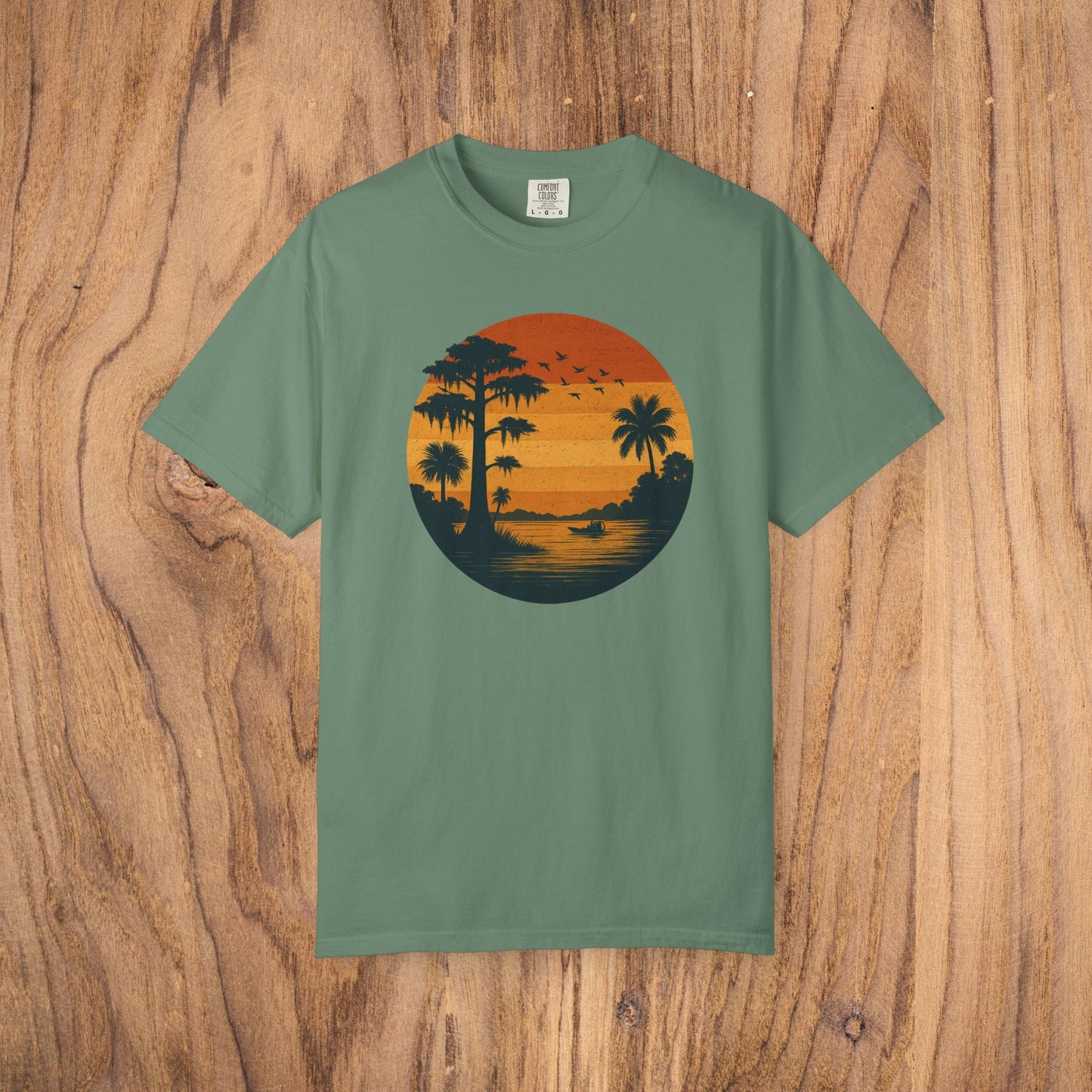 Unisex Garment-Dyed Sunset Tee in soft green showcasing a sunset graphic with palm silhouettes, great for everyday comfort.