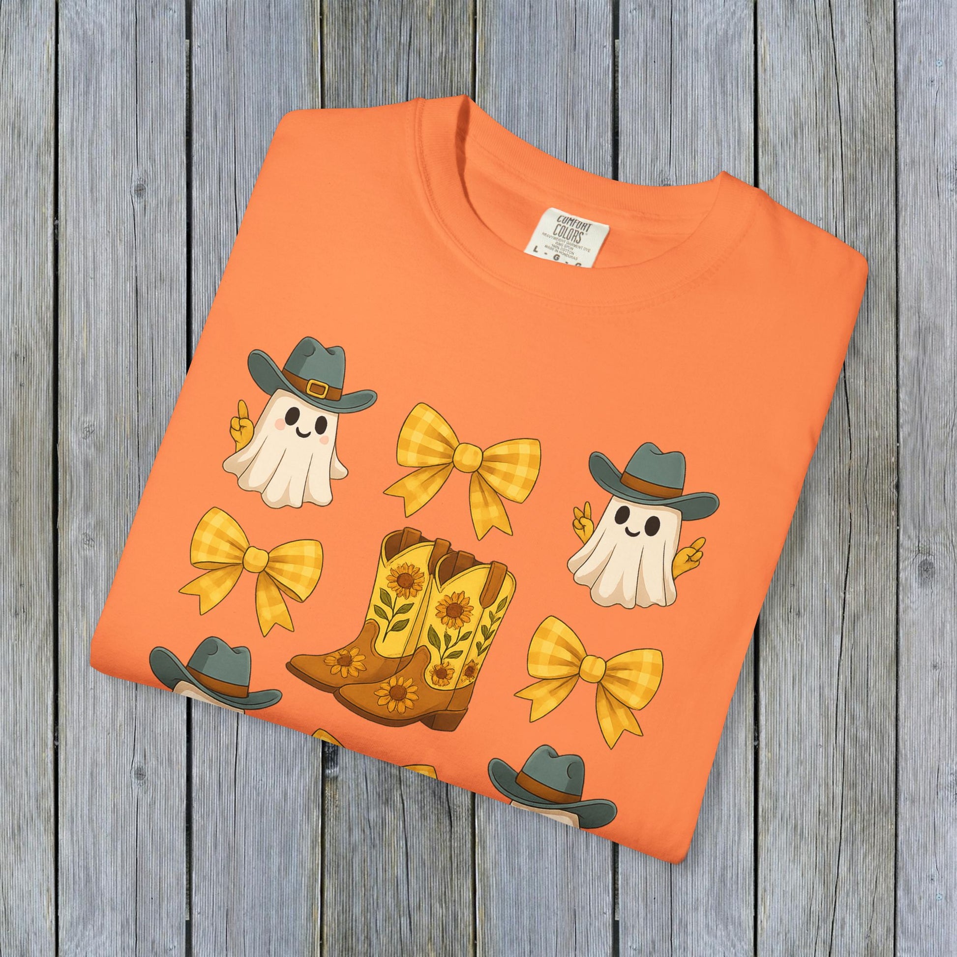 Beautifully displayed Cute Halloween T-Shirt with a vibrant orange color featuring ghosts and cowboy boots. A perfect addition to your eco-friendly fall fashion collection.