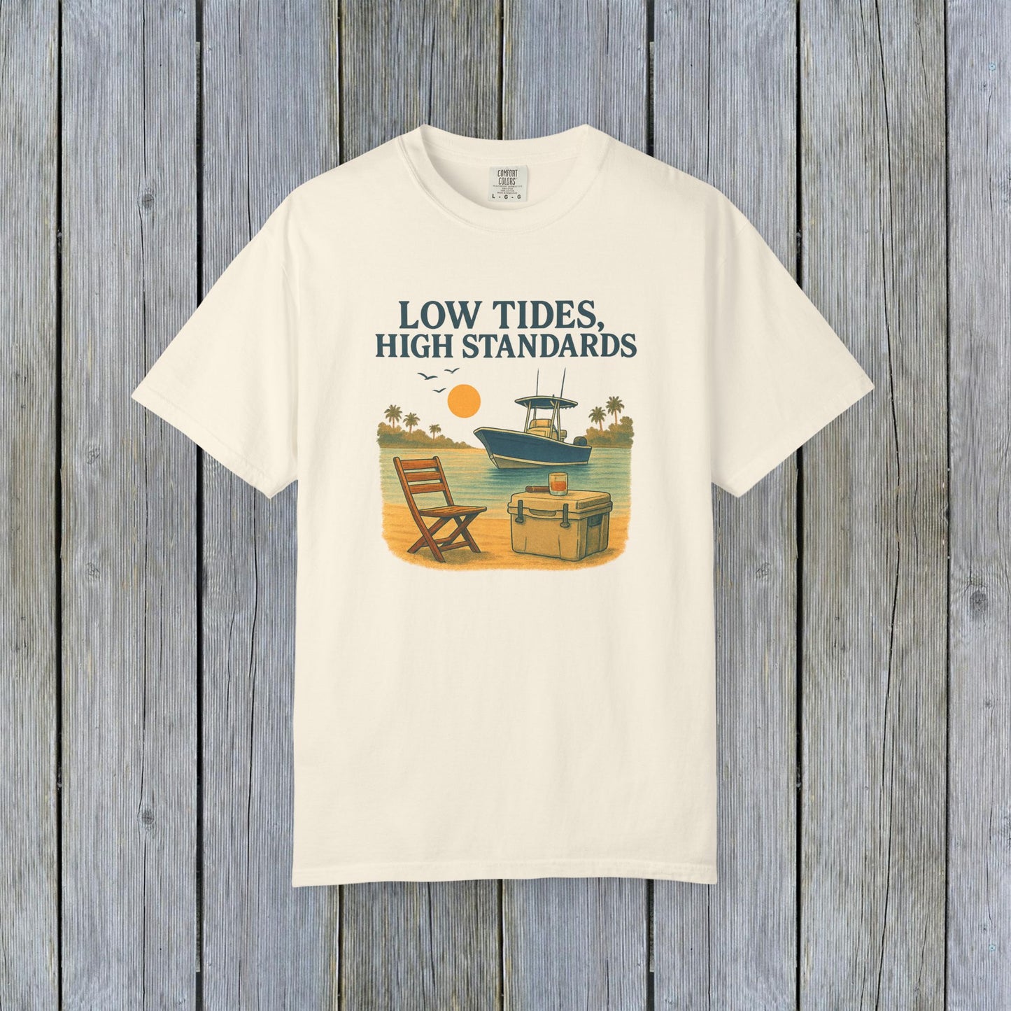 Garment-Dyed Low Tides High Standards T-Shirt in cream, showcasing an artistic beachfront design with a chair and boat. Crafted from soft 100% US cotton, offered in sizes S-4XL for a comfortable fit.