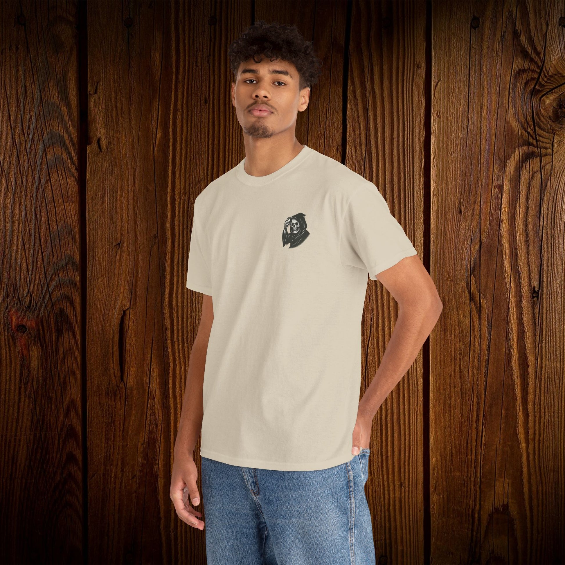 Front view of a Spooky Halloween Graphic Tee with a ghost print on a unisex cotton shirt, worn by a young man in a light color, displayed against a rustic wooden backdrop.