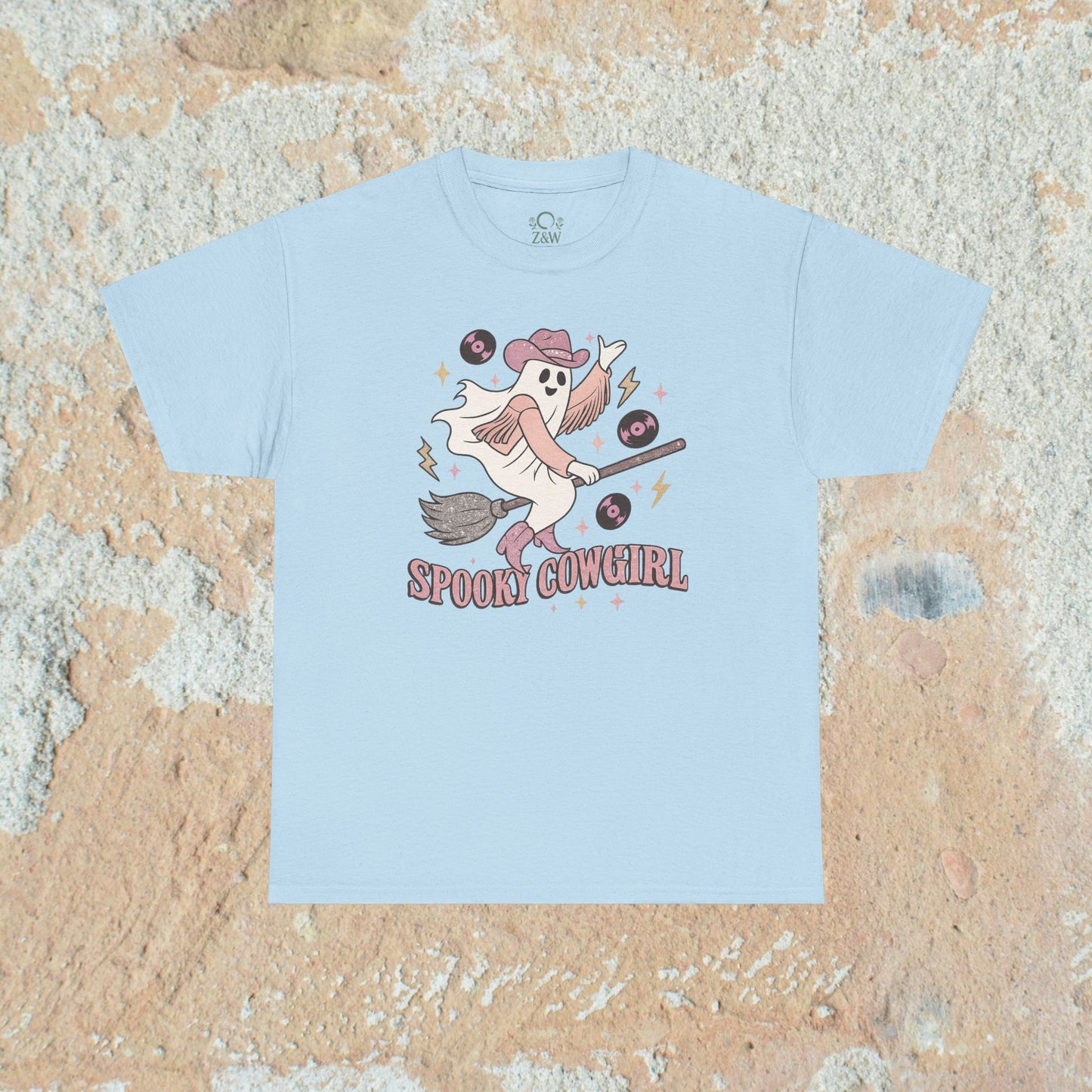 Light blue Spooky Cowgirl Graphic Tee featuring a whimsical ghost cowgirl riding a broom, perfect for Halloween enthusiasts.