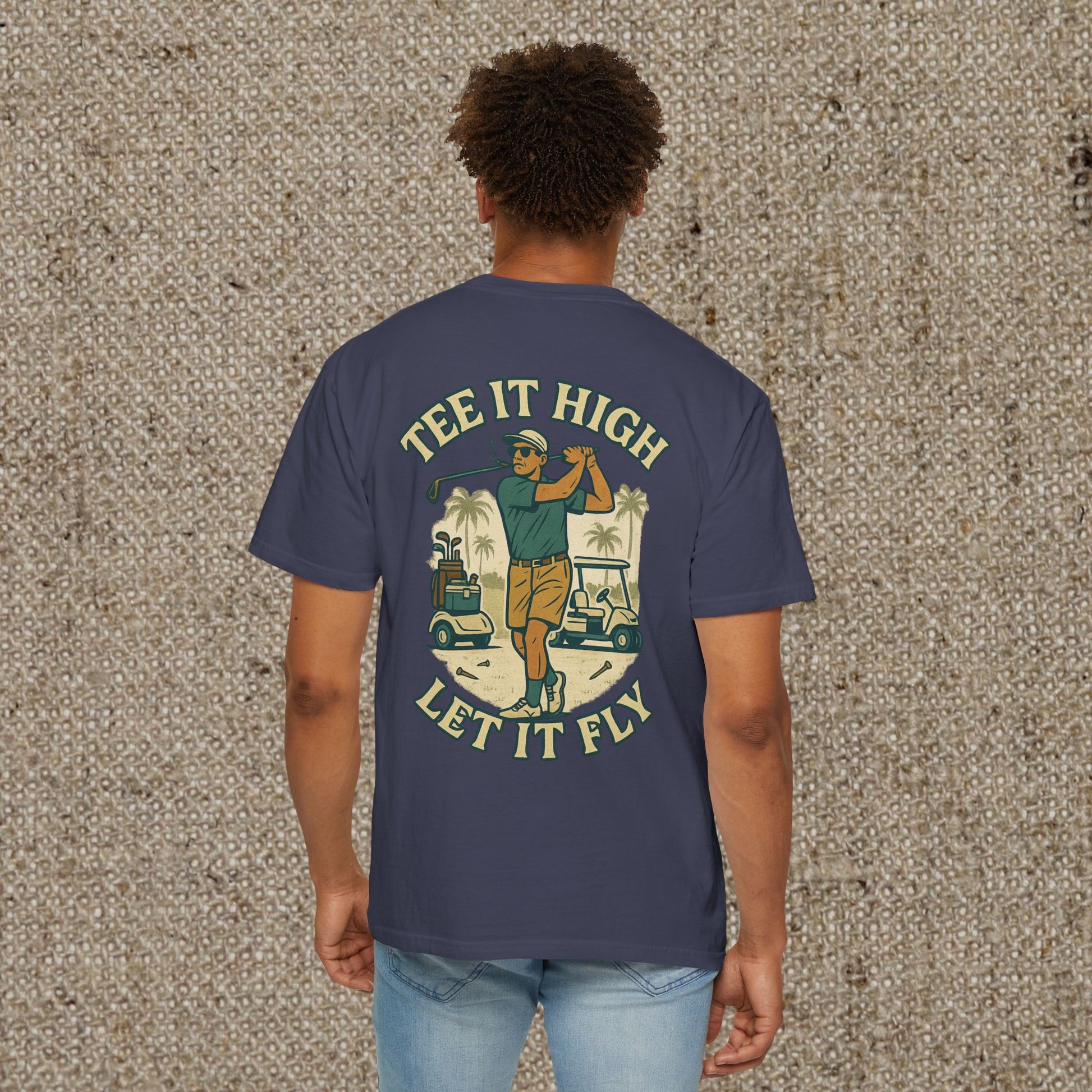 Back view of a model in the Tee It High Let It Fly Graphic Tee, featuring a vibrant graphic of a golfer with carts, perfect for golf enthusiasts looking for style and comfort.