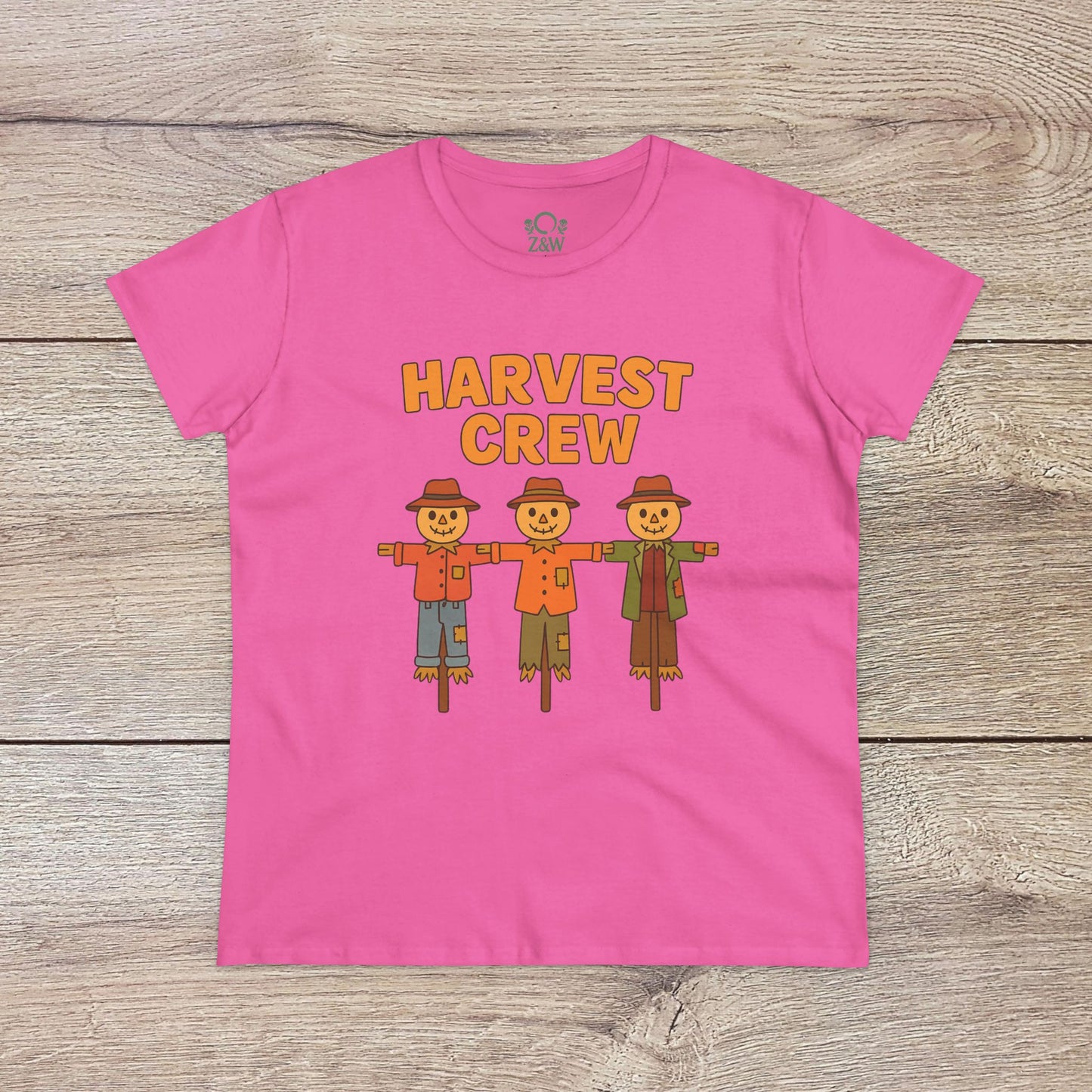 Harvest Crew Halloween T-Shirt in bright pink, featuring whimsical scarecrows and the slogan 'Harvest Crew'. Made from soft 100% ring-spun cotton, it ensures a comfortable and stylish fit for Halloween.