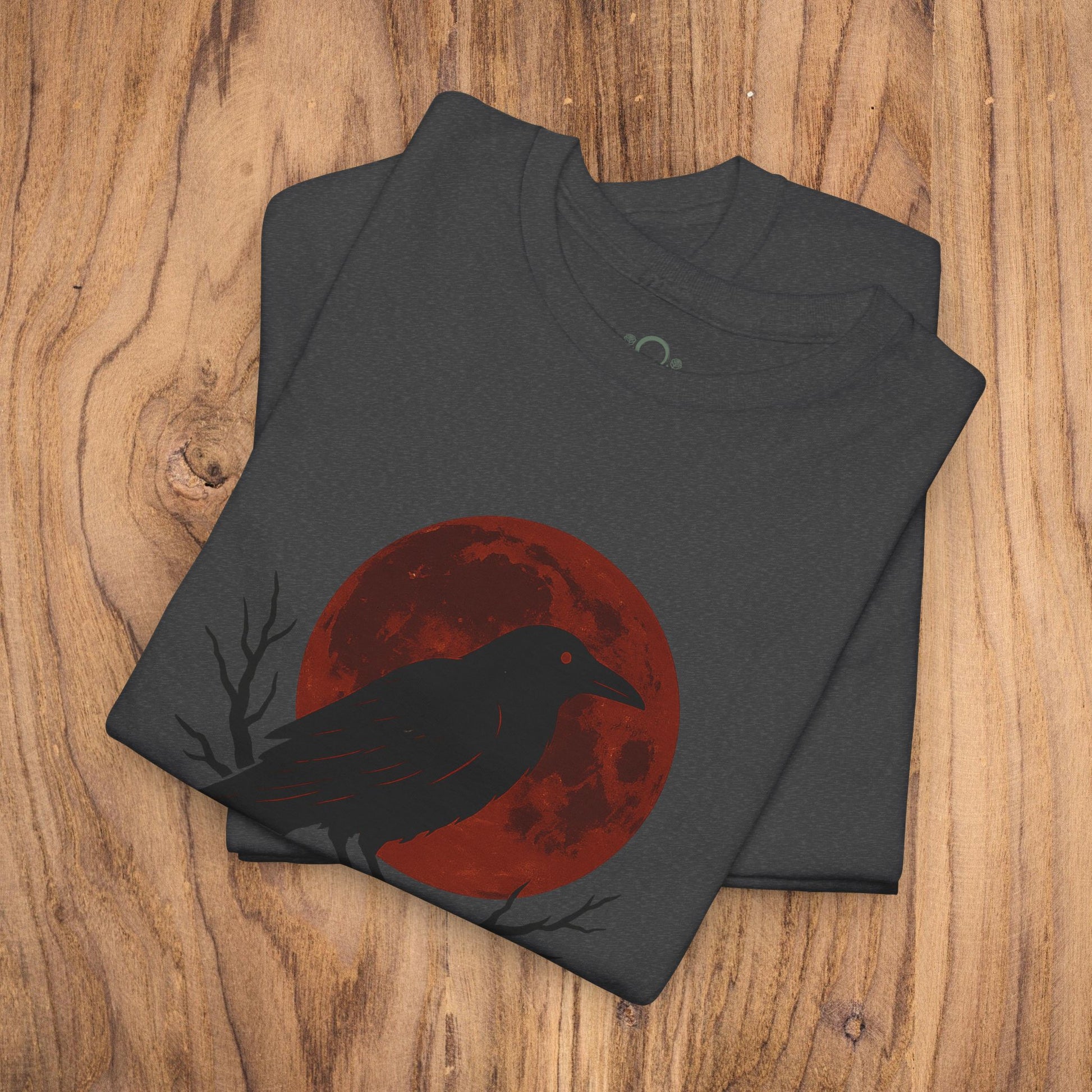 Gothic Raven T-Shirt with a striking design featuring a raven silhouette against a red moon, perfect for Halloween celebrations. Heavy cotton tee, unique spooky gift, and casual fall fashion.