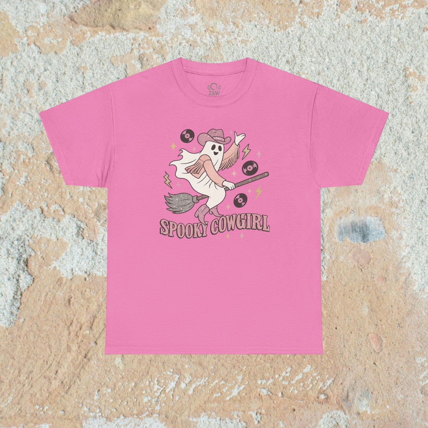 Spooky Cowgirl Graphic Tee in vibrant pink featuring a playful ghost with a hat, holding a broom and surrounded by musical symbols, perfect for Halloween and casual wear.