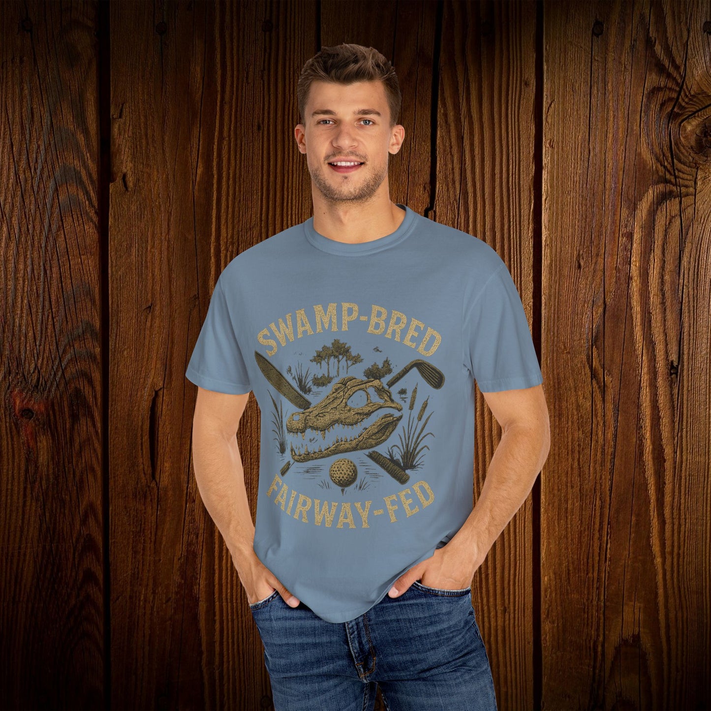Model showcasing the Unisex Swamp-Bred Fairway-Fed Tee in light blue, with a vibrant graphic featuring a golf club and swamp imagery, perfect for casual wear.