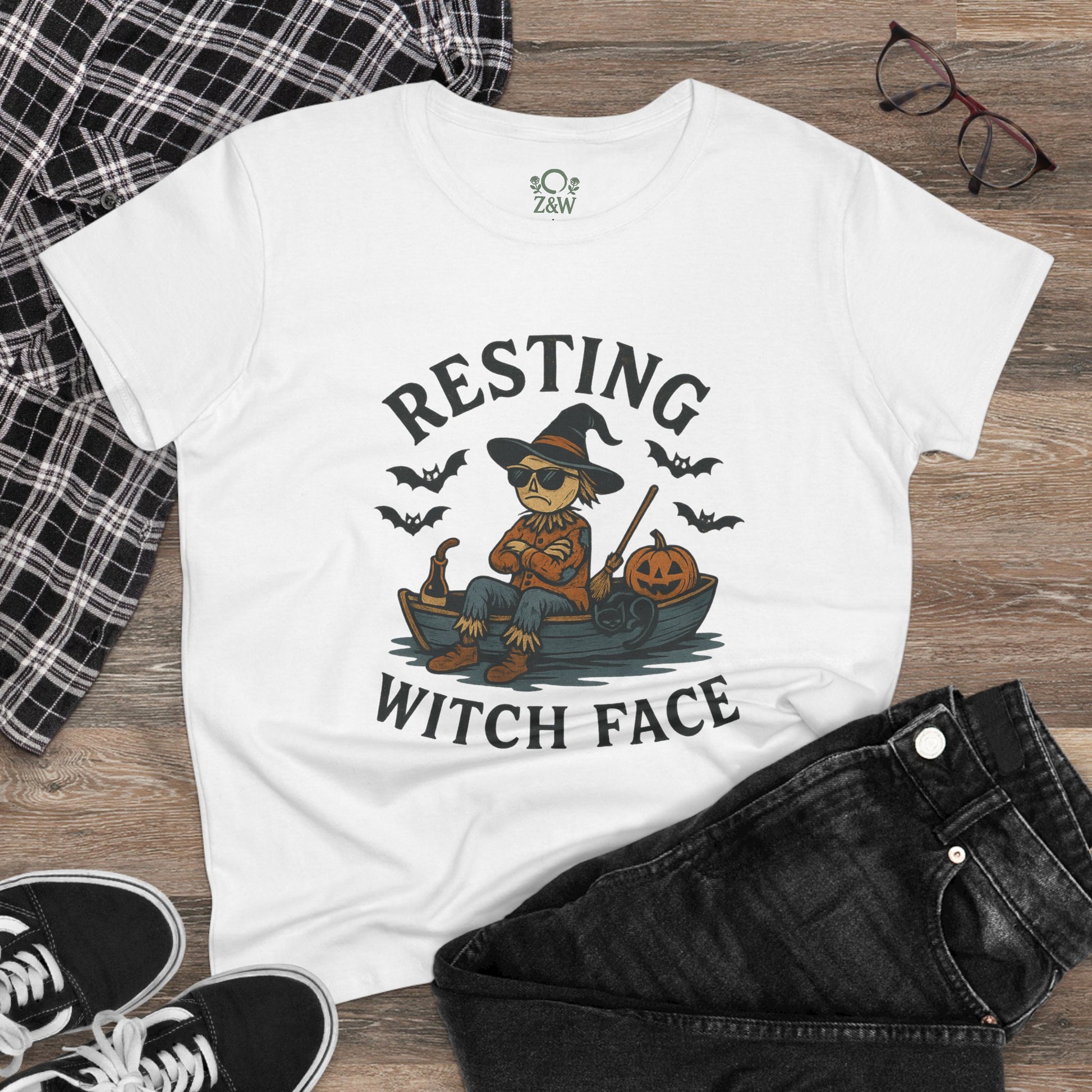 Styled front view of the 'Resting Witch Face Halloween T-Shirt for Women, Unisex Funny Cotton Tee for Parties and Gifts', featuring a witch design, paired with black jeans and sneakers on a wooden floor.